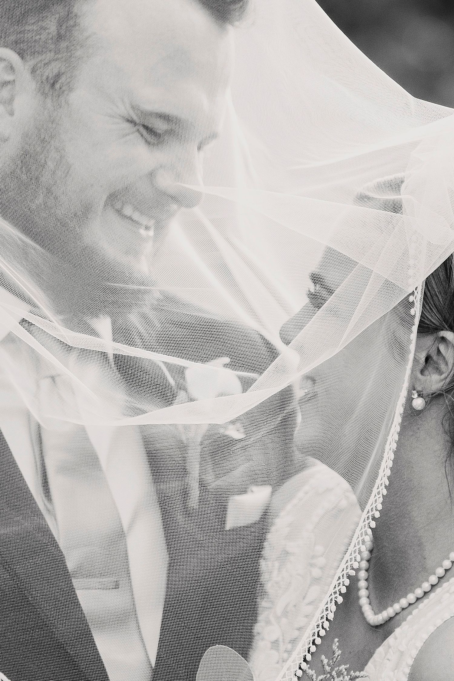 husband and wife underneath a veil by Claire Malaby Photography