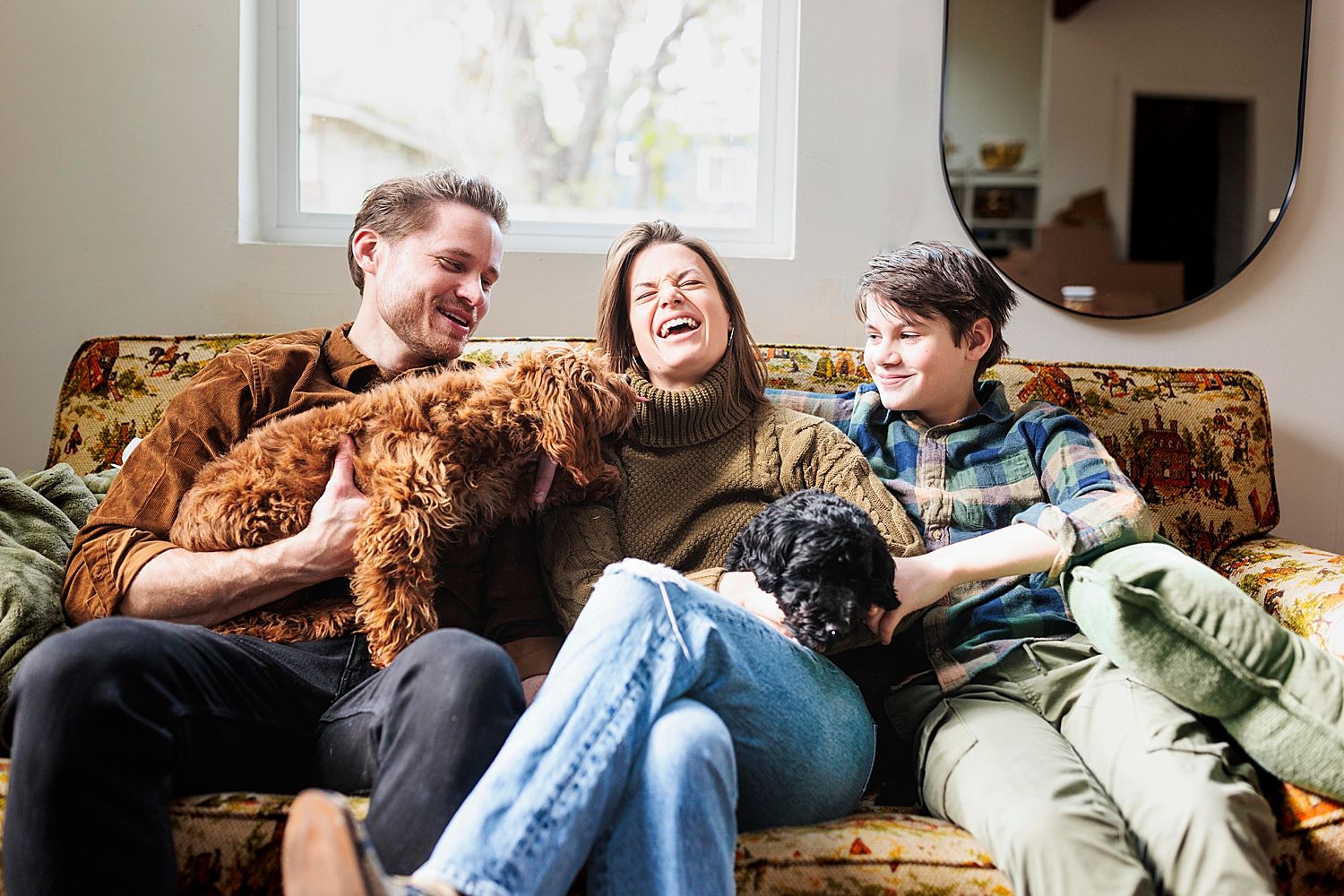 mom laughs as pups reach for her on couch for lifestyle session in studio