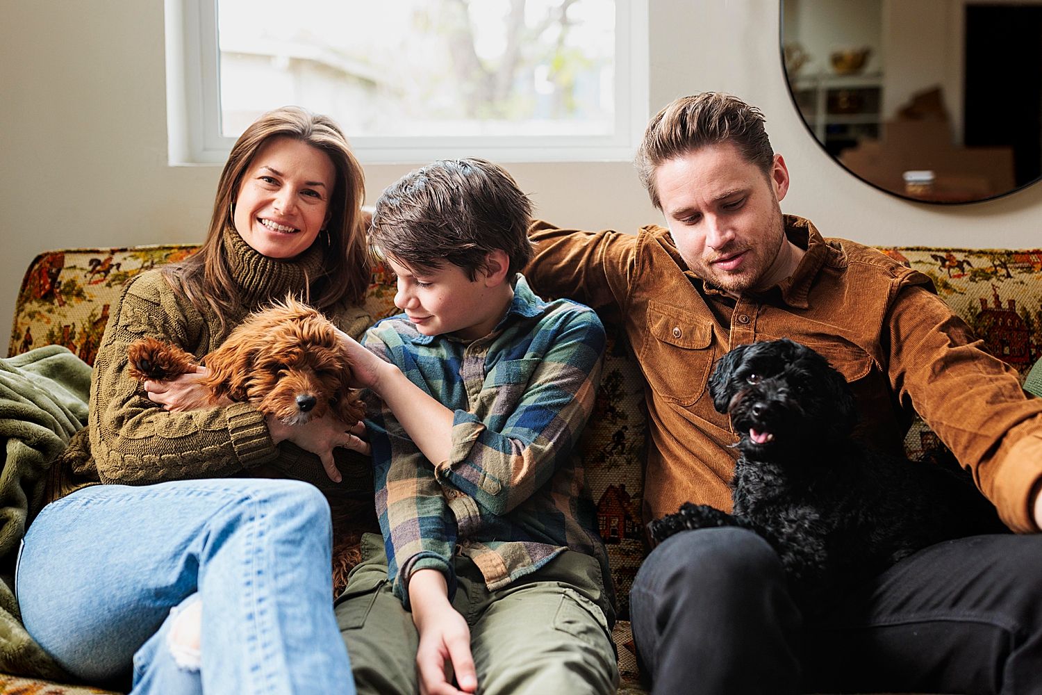 child pets dog on mom's lap on the couch by Claire Malaby Photography