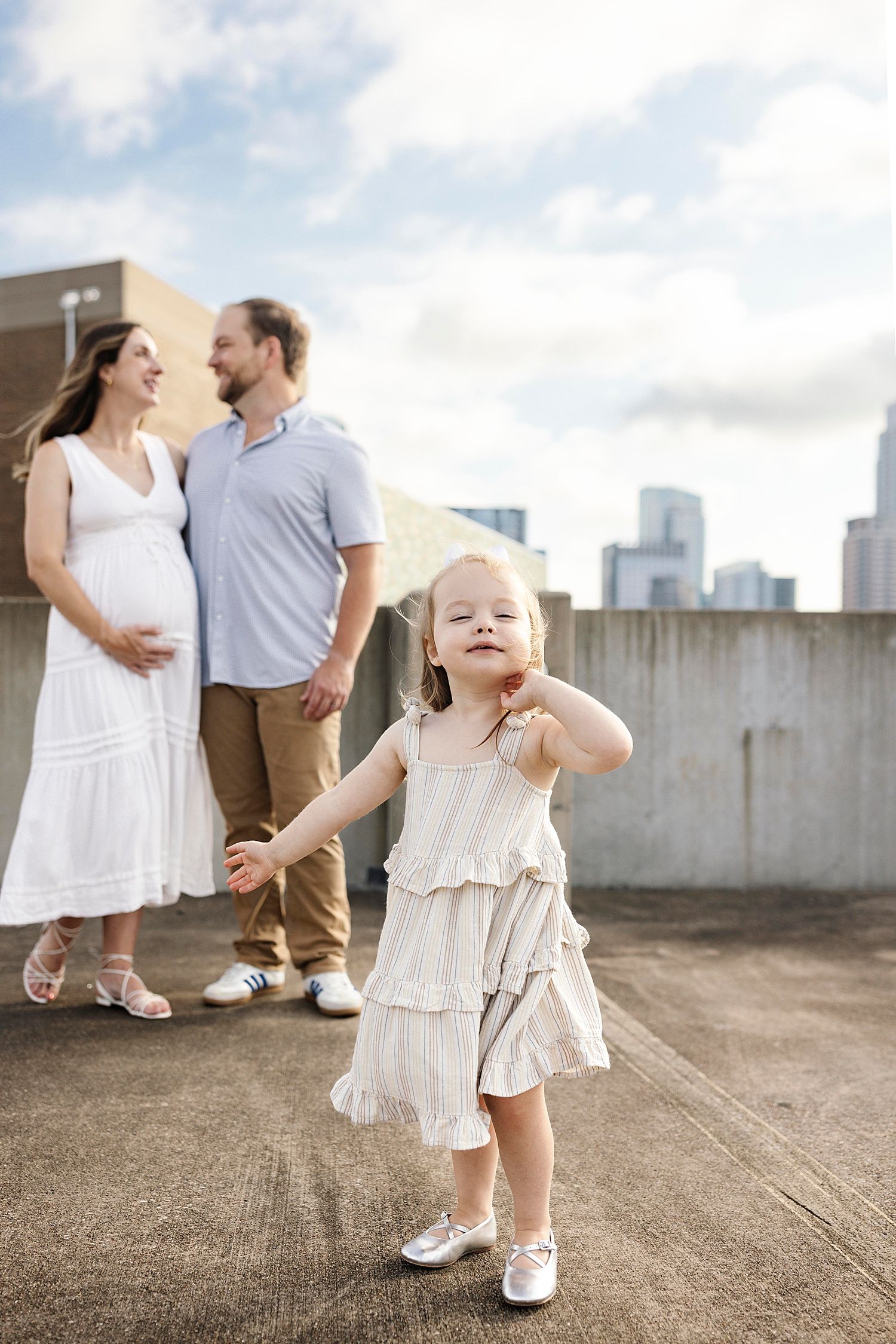 toddler runs forward as mom & dad look at each other in background  by Austin family photographer