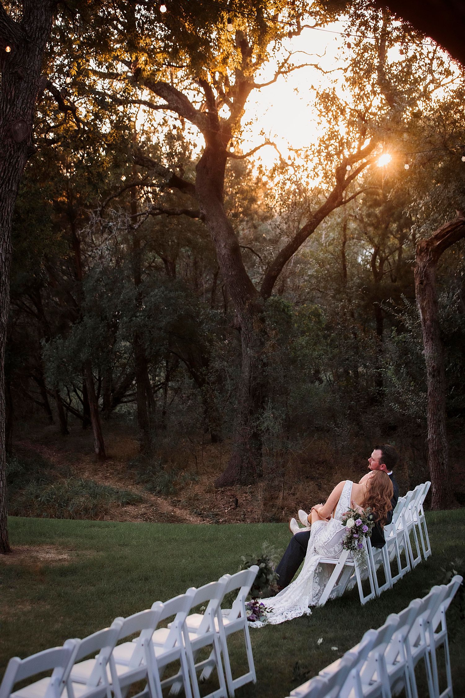 newlyweds sit on ceremony chairs alone in golden hour by Claire Malaby Photography