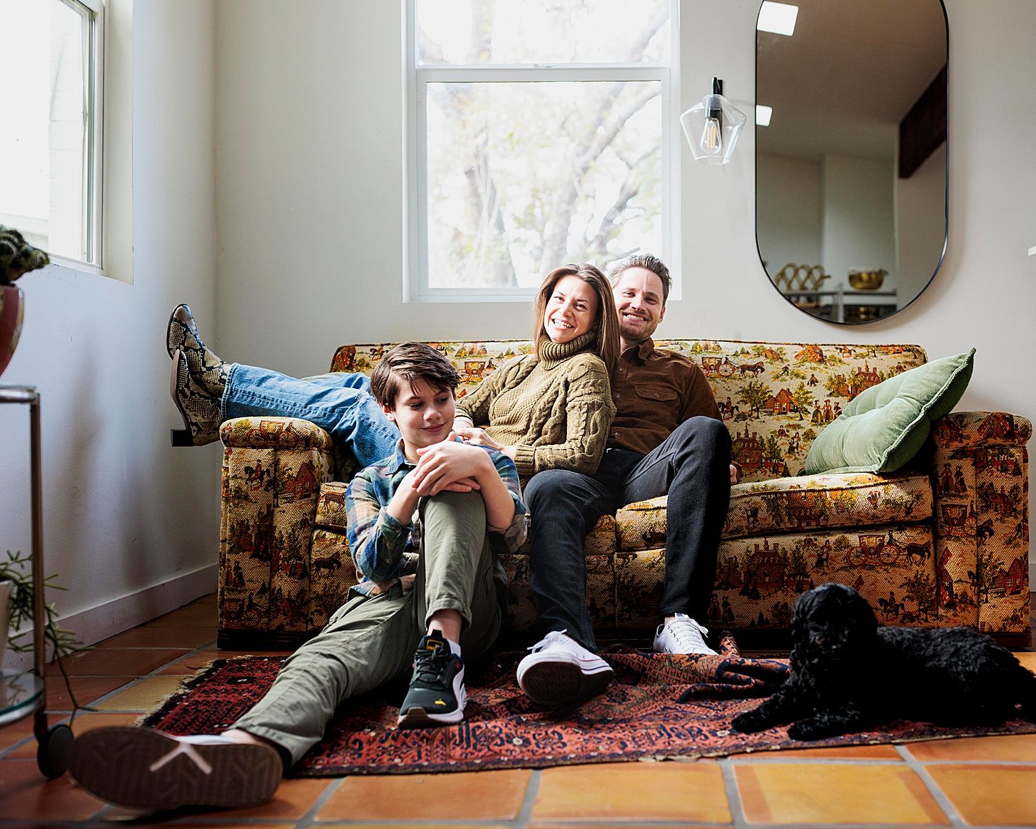 parents relax on studio couch while son and pups sit on floor by Claire Malaby Photography