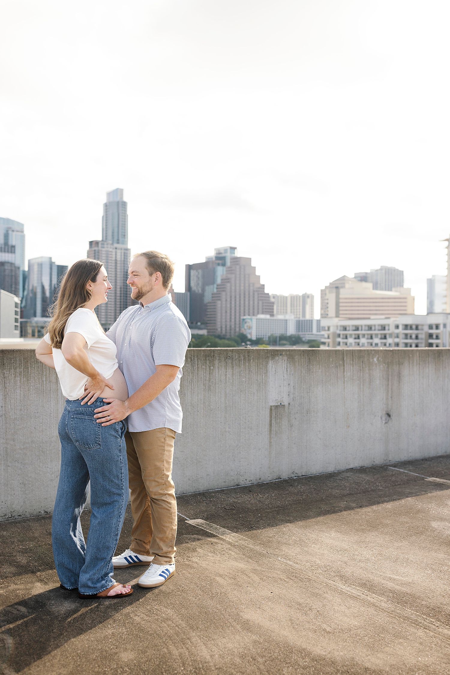 married couple smile and hug over bump by Austin family photographer