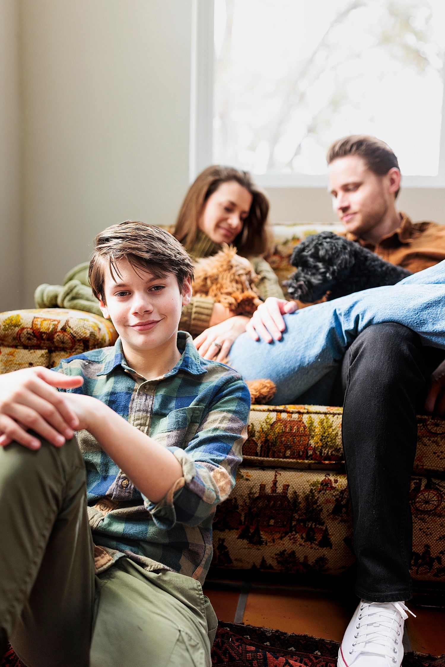 son sits on floor in front of couch for lifestyle session in studio