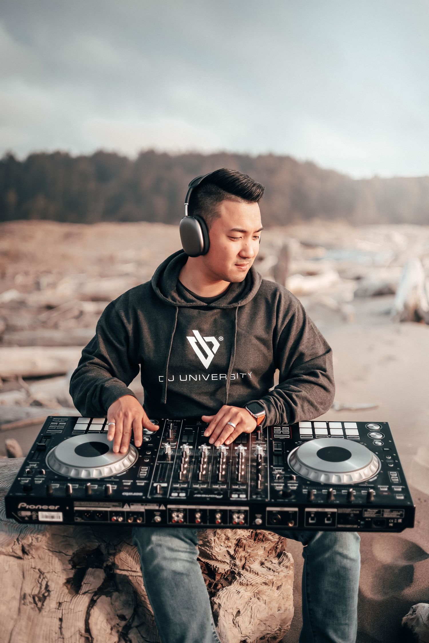 Outdoor lifestyle shot of a DJ mixing music on a beach at sunset, blending minimal style, warm tones, and creative adventure energy.