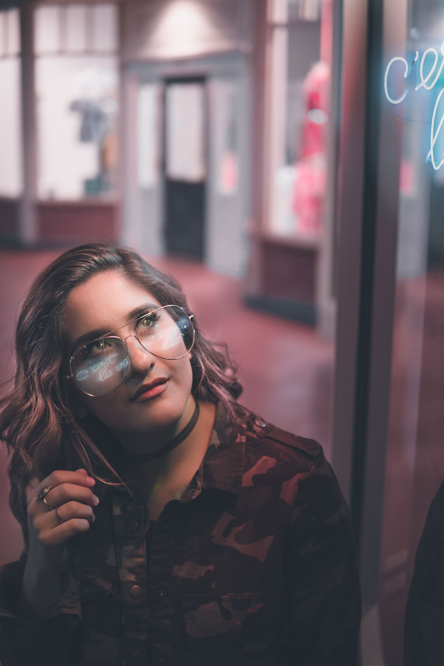 Moody, minimal portrait of a woman by neon reflections, with soft pink light creating an urban, cinematic atmosphere and dreamy expression