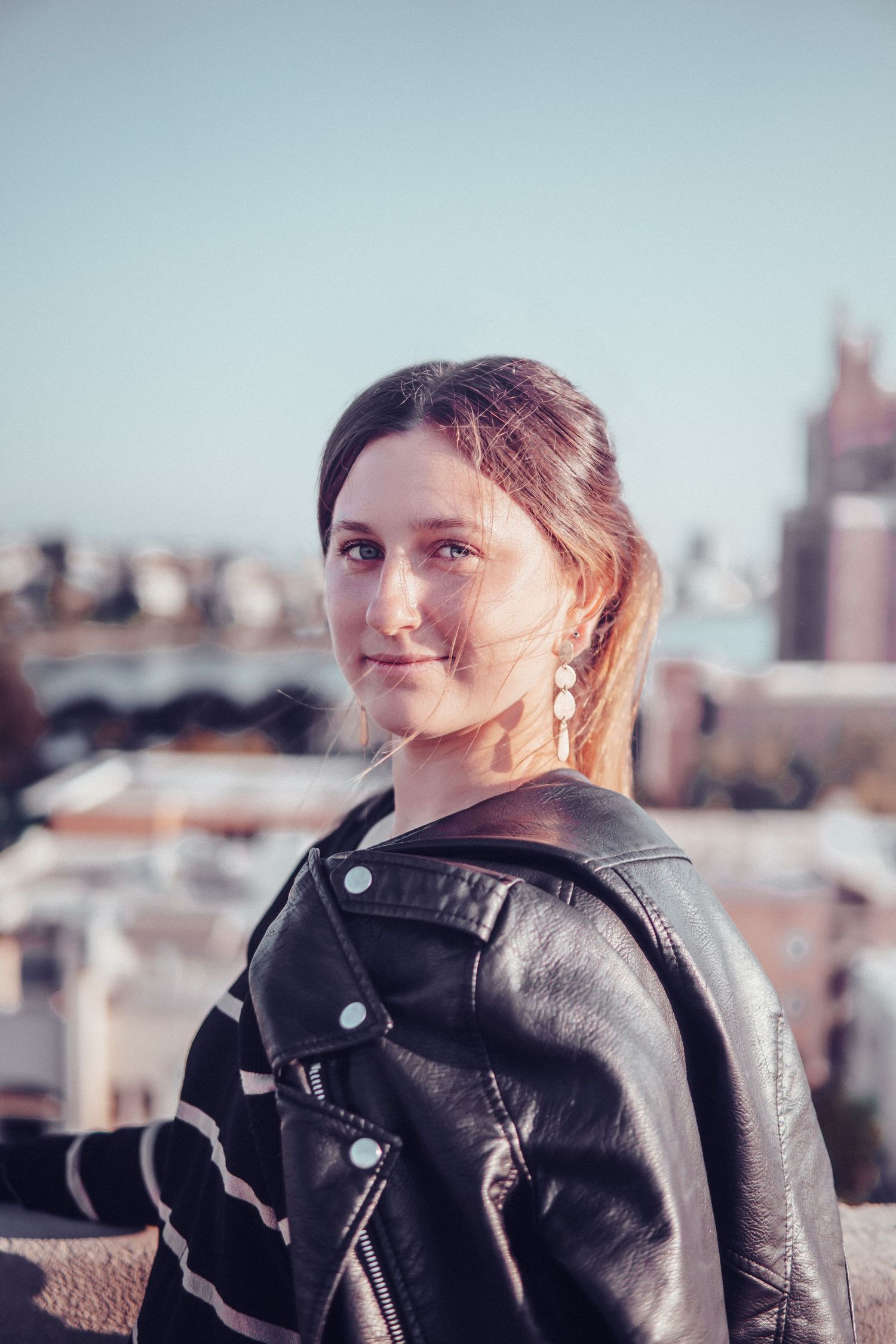 Woman walking along a rooftop during sunset with soft golden light and urban skyline views creating a calm city adventure