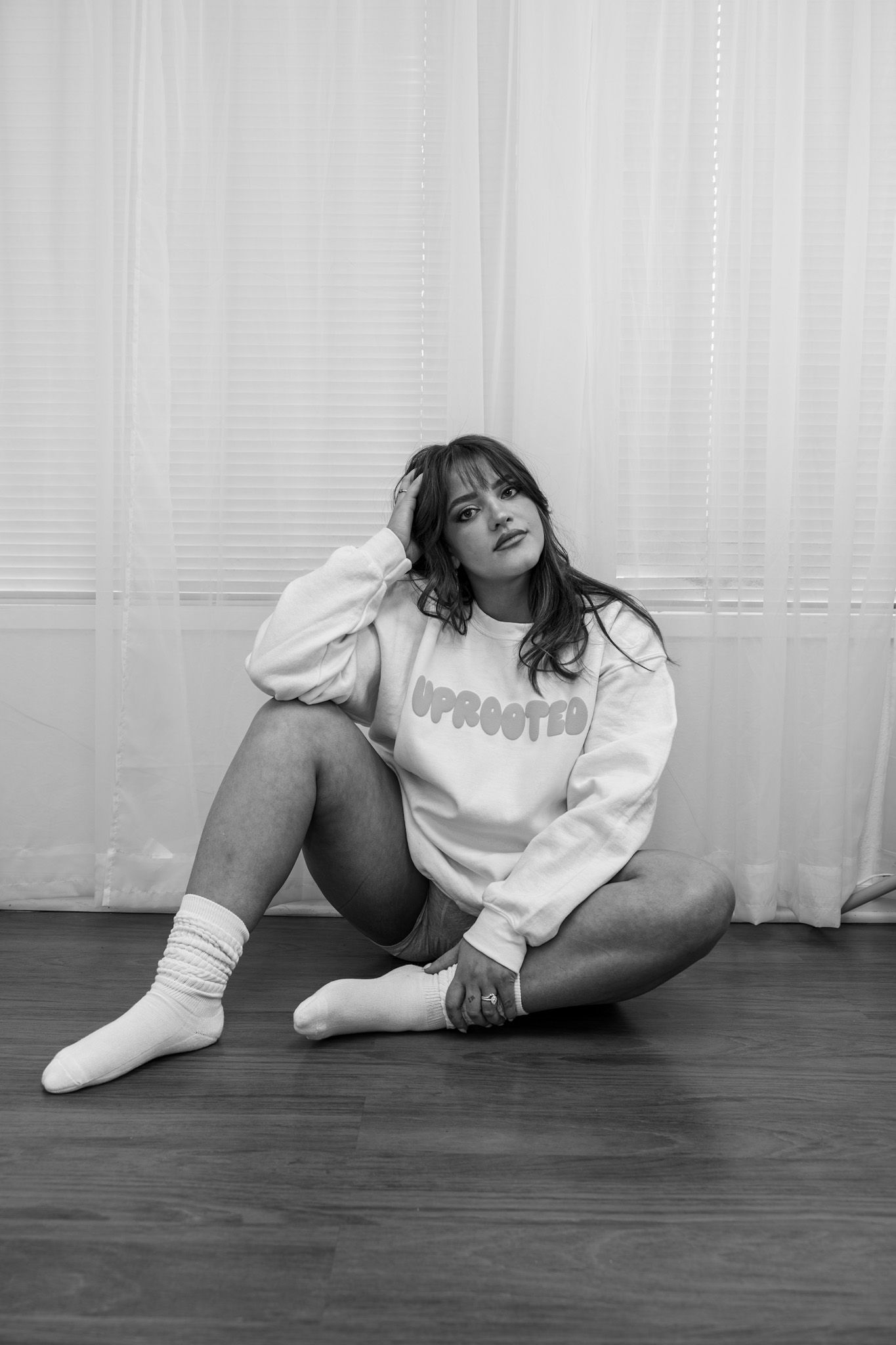 Black and white artistic photo series showing a person in white clothing lying on a dark hardwood floor.