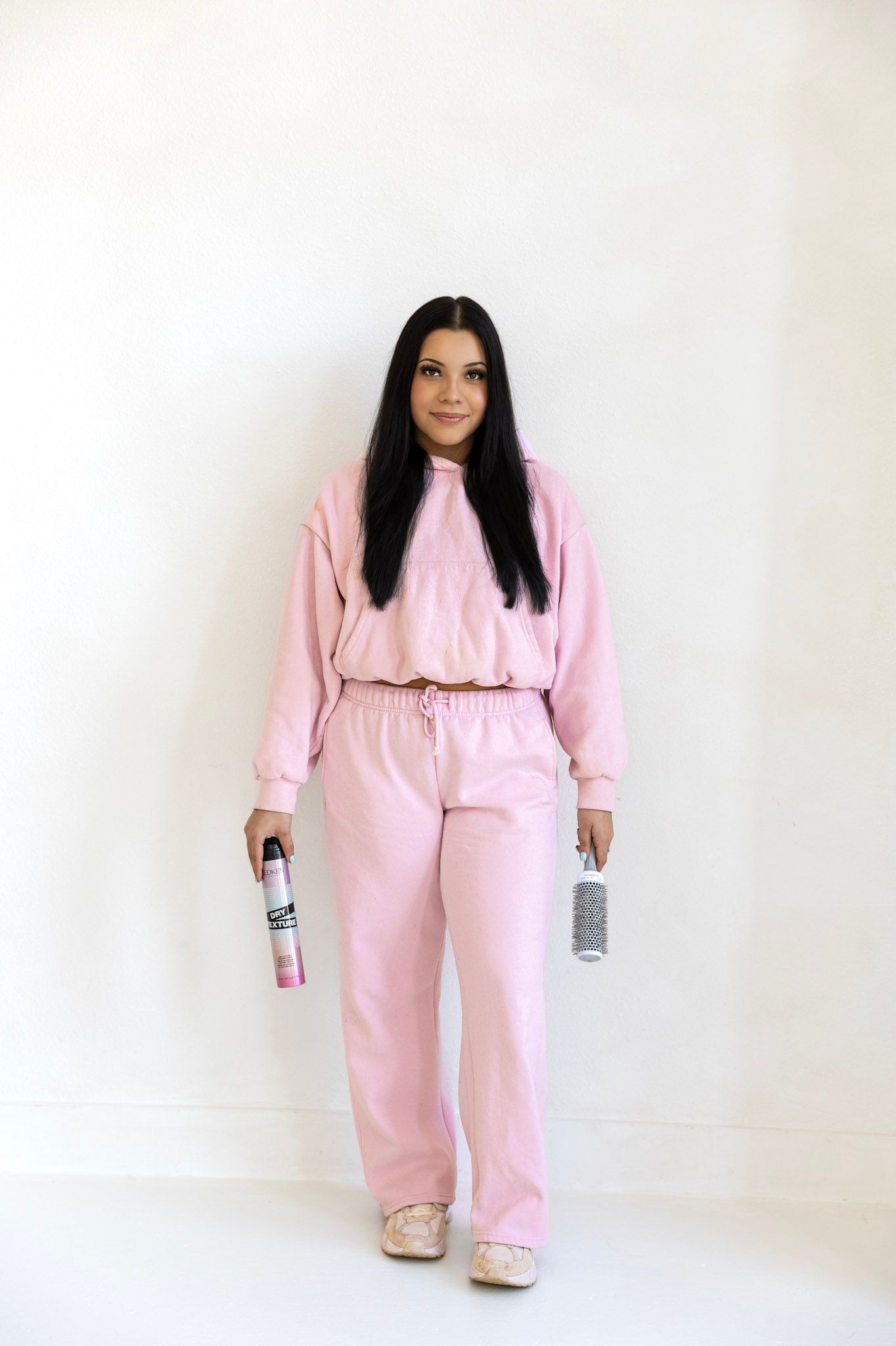 Person wearing cozy pink loungewear set holding canned beverages against white background.