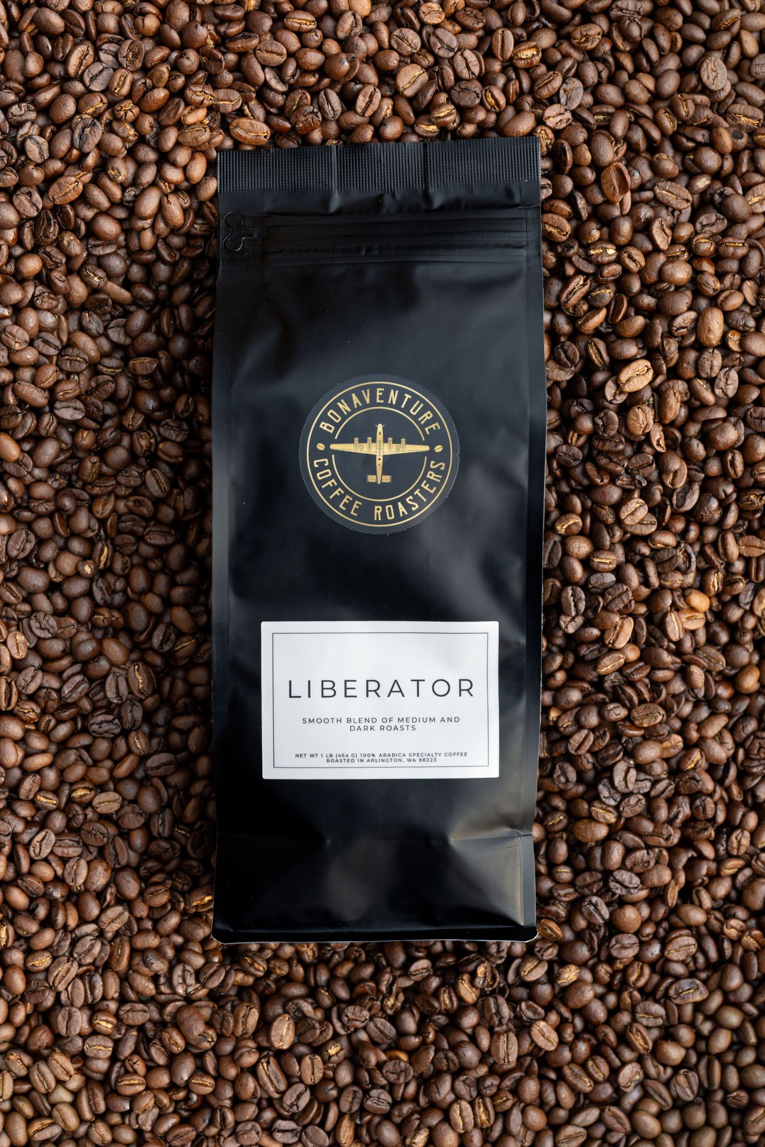Bonaventure Coffee Roasters Liberator blend in a black bag surrounded by roasted coffee beans.