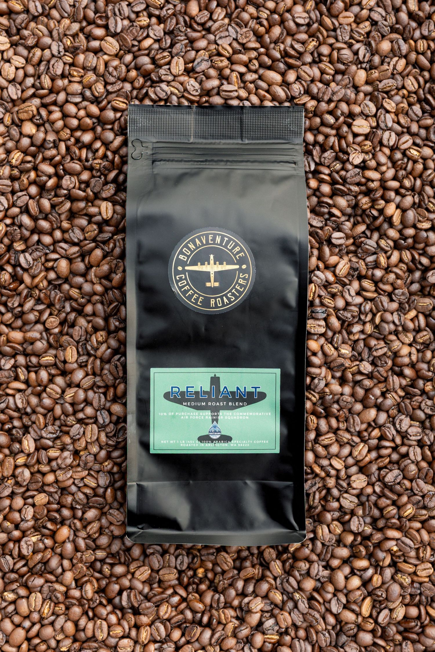 Black bag of Reliant medium roast coffee by Bonaventure Coffee Roasters, surrounded by roasted coffee beans.