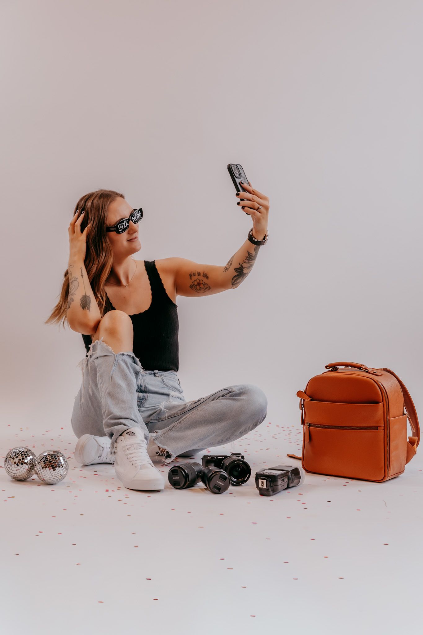 A lifestyle product photoshoot with a brown leather bag, roller skates, and casual loungewear against a white backdrop.