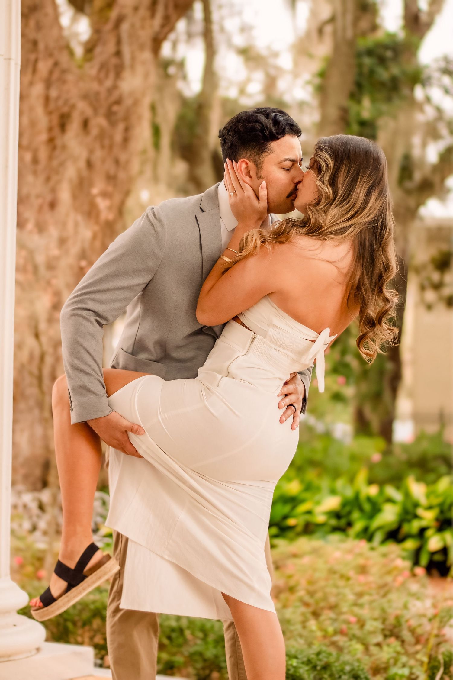 Romantic engagement photos of couple embracing in outdoor garden setting.