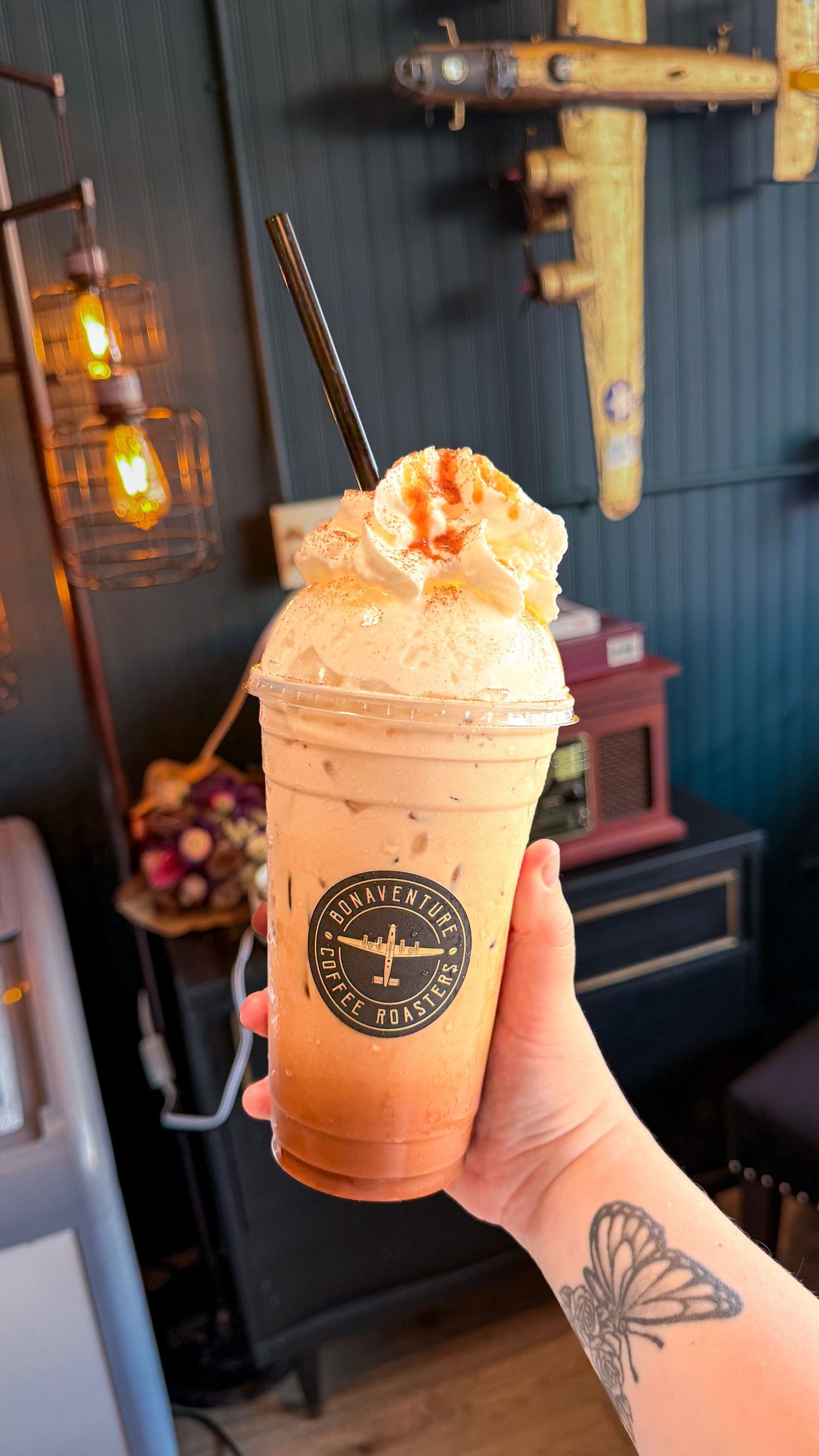 Hand holding a Bonaventure Coffee Roasters iced blended drink topped with whipped cream and caramel drizzle.