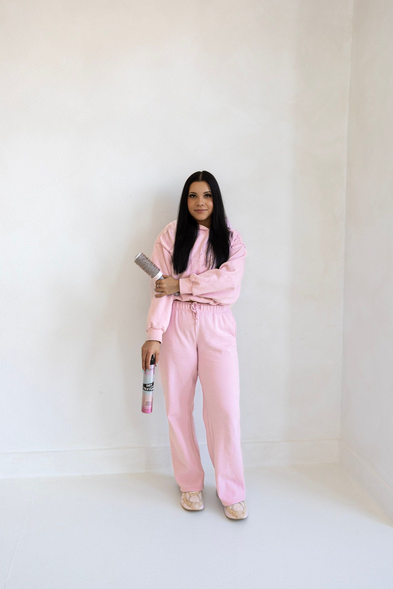 A person wearing a cozy pink loungewear set poses against a white background in three different positions.