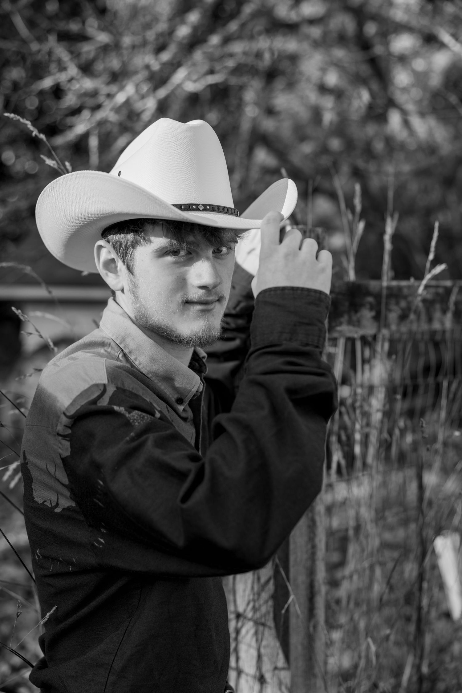 A figure in a cowboy hat and dark jacket shown in a black and white photo series against a wooded background.