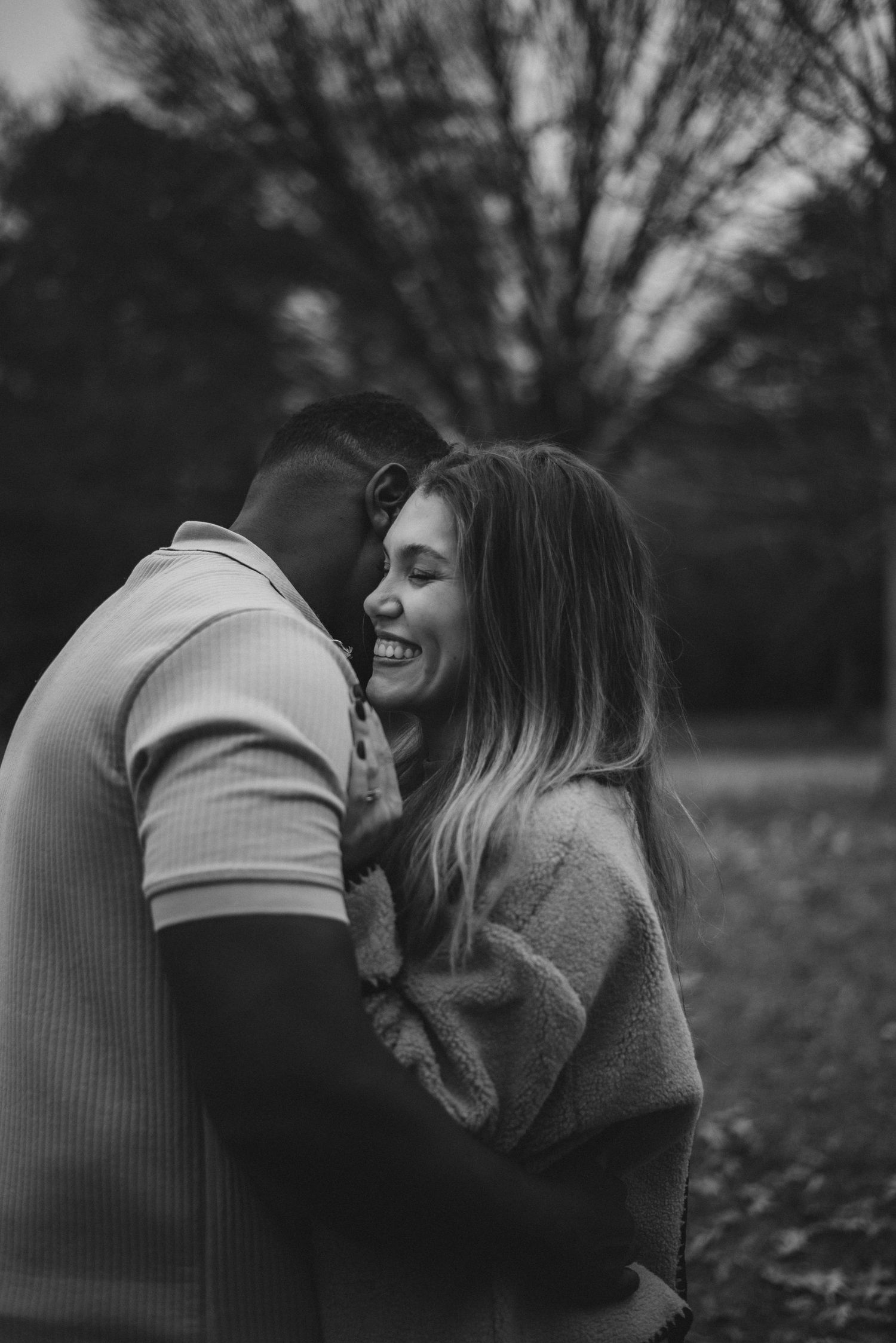 A black and white photo series showing a romantic couple embracing and laughing together in a natural outdoor setting.