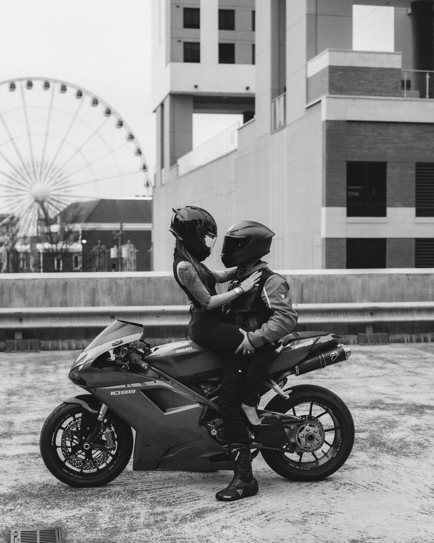 A black motorcycle is parked on a rooftop with a ferris wheel visible in the background creating a dramatic silhouette.