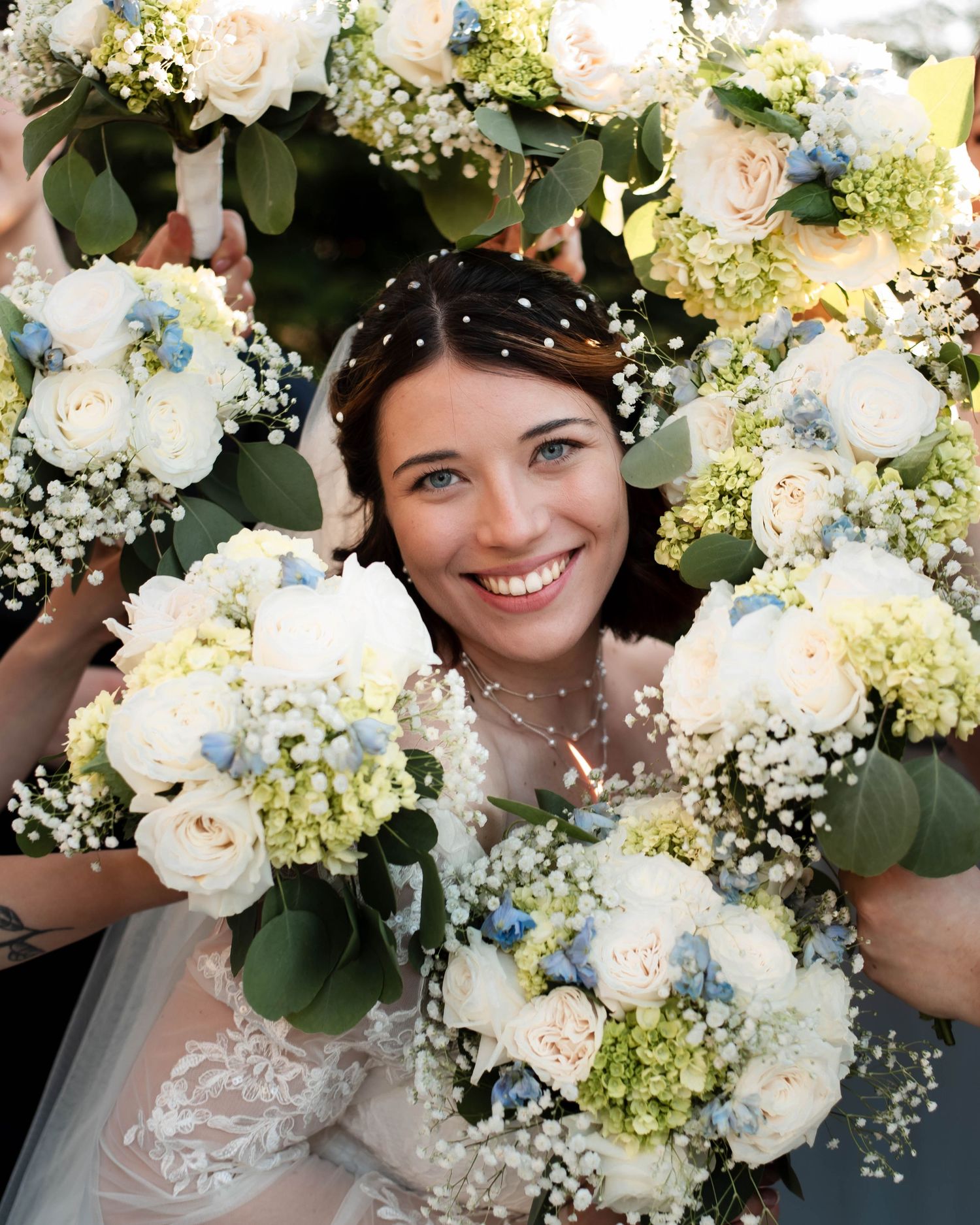 Elegant bridal bouquet featuring white roses, baby's breath, and lush greenery against a soft background.