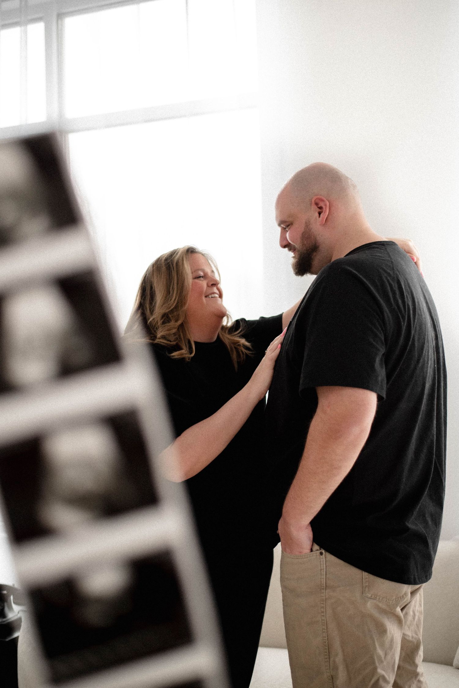 A couple in casual attire share an intimate moment against a white background in a series of romantic photos.