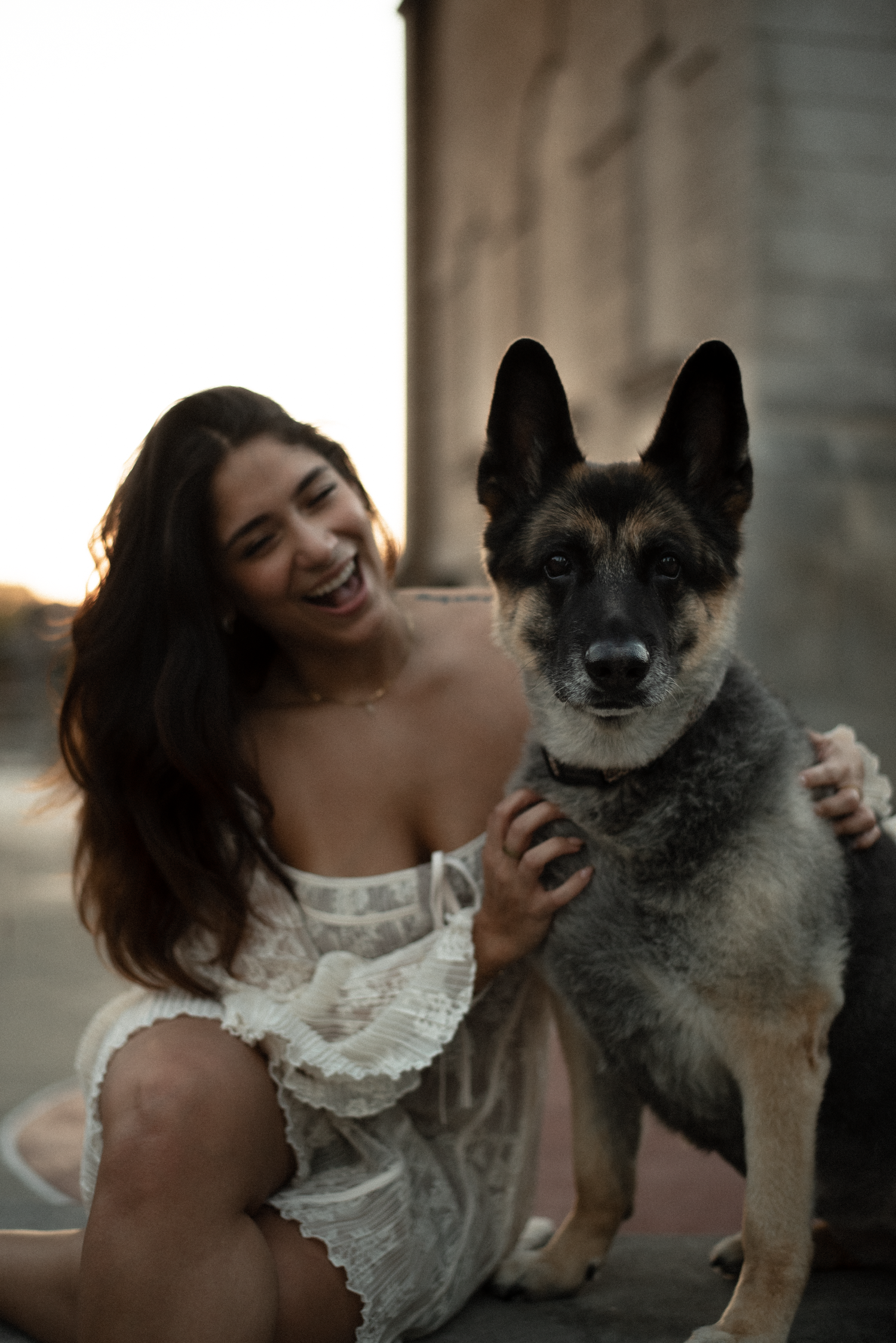 A joyful moment captured between someone in a white lace top and their happy Norwegian Elkhound dog at sunset.