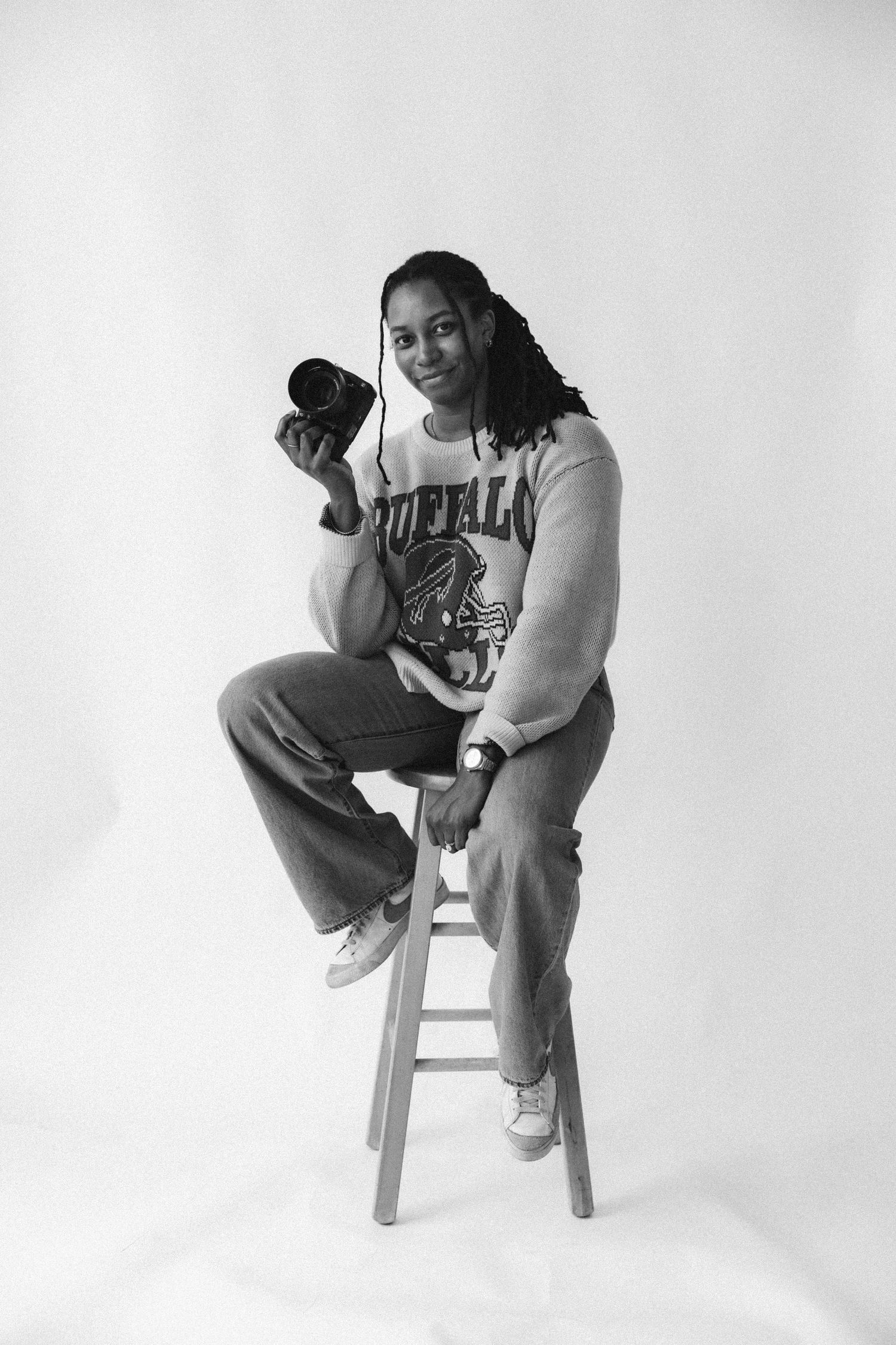 Black and white studio portraits show someone seated on a white chair in casual clothing against a plain background.