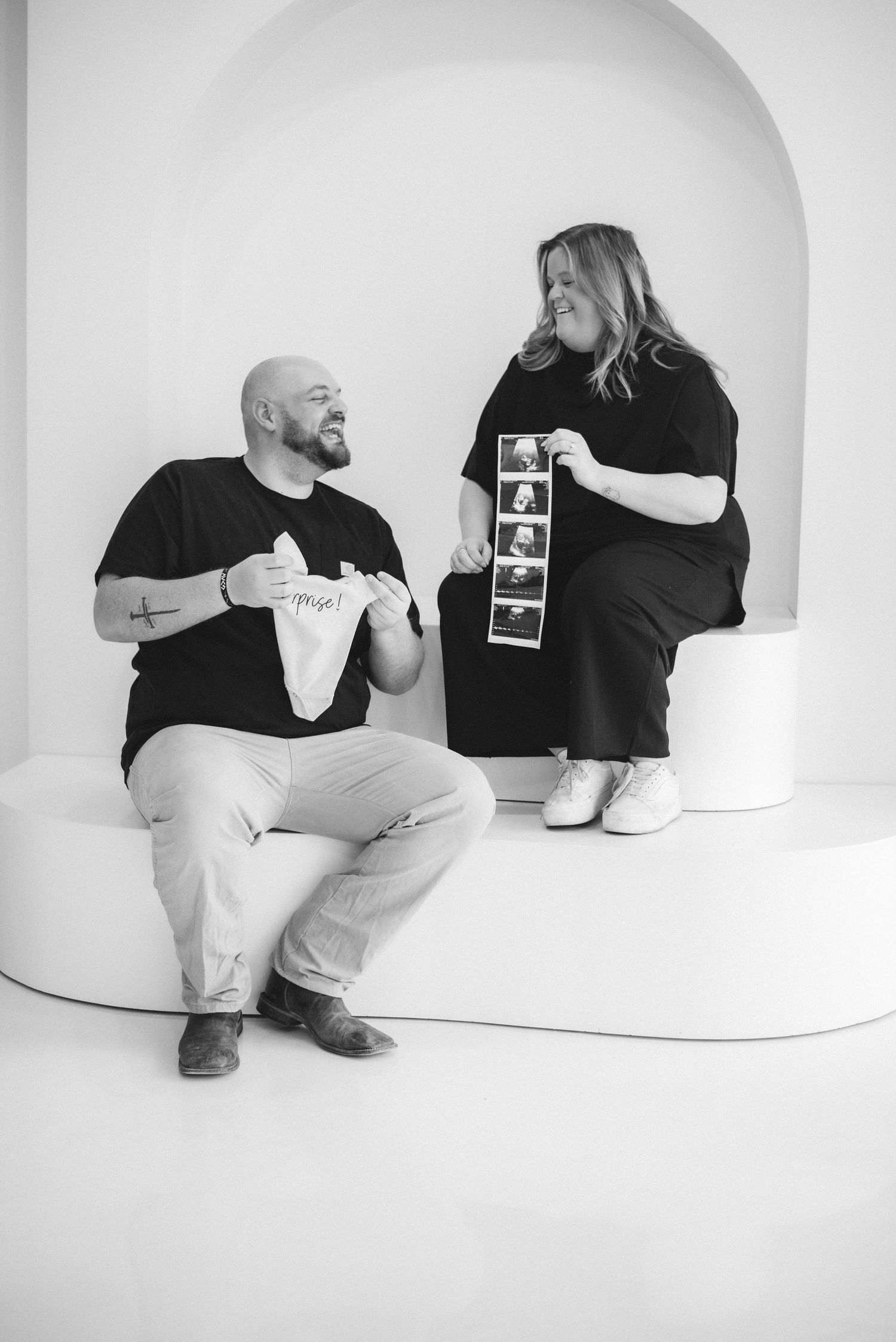 Black and white photo series showing a couple holding ultrasound photos in various poses against a white backdrop.