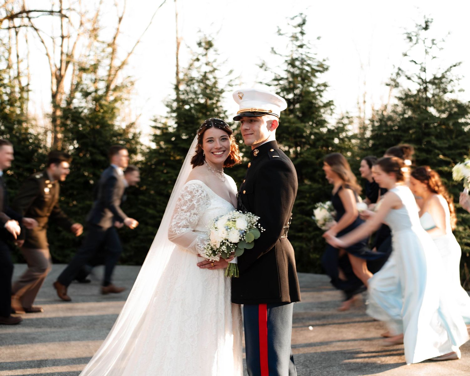 A romantic outdoor wedding scene with a couple dancing at sunset among pine trees and guests.