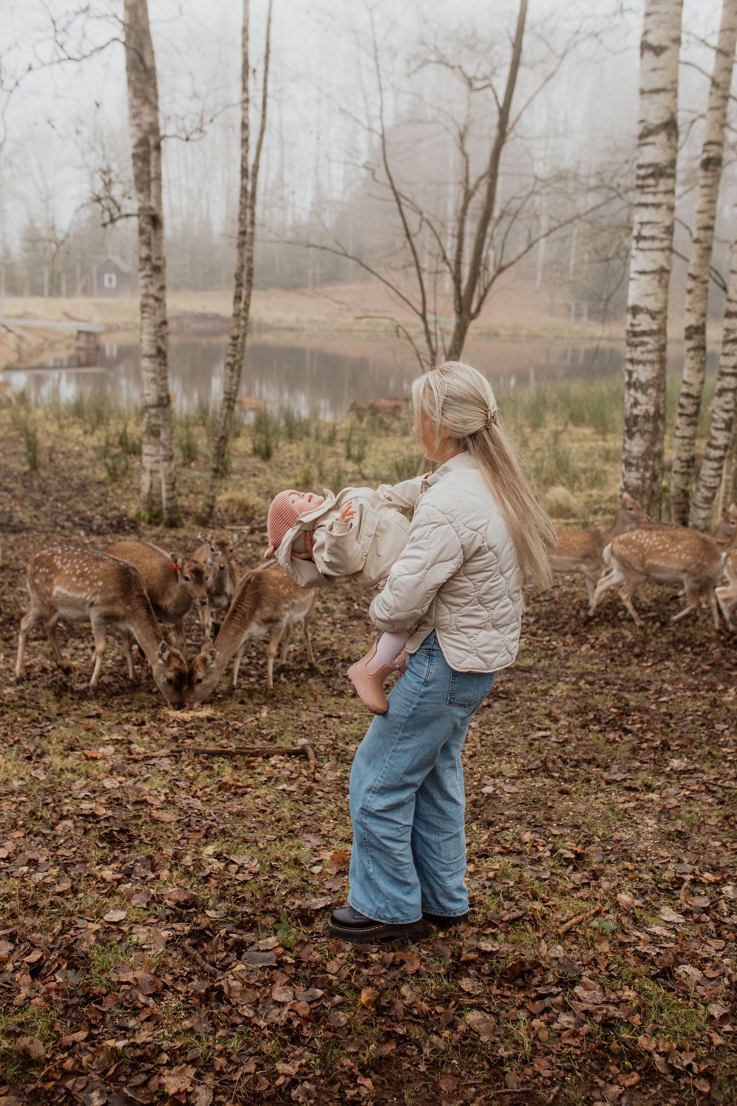 Natural family portrait of parents and children laughing together during an outdoor photography session in Latvia. with deers running around