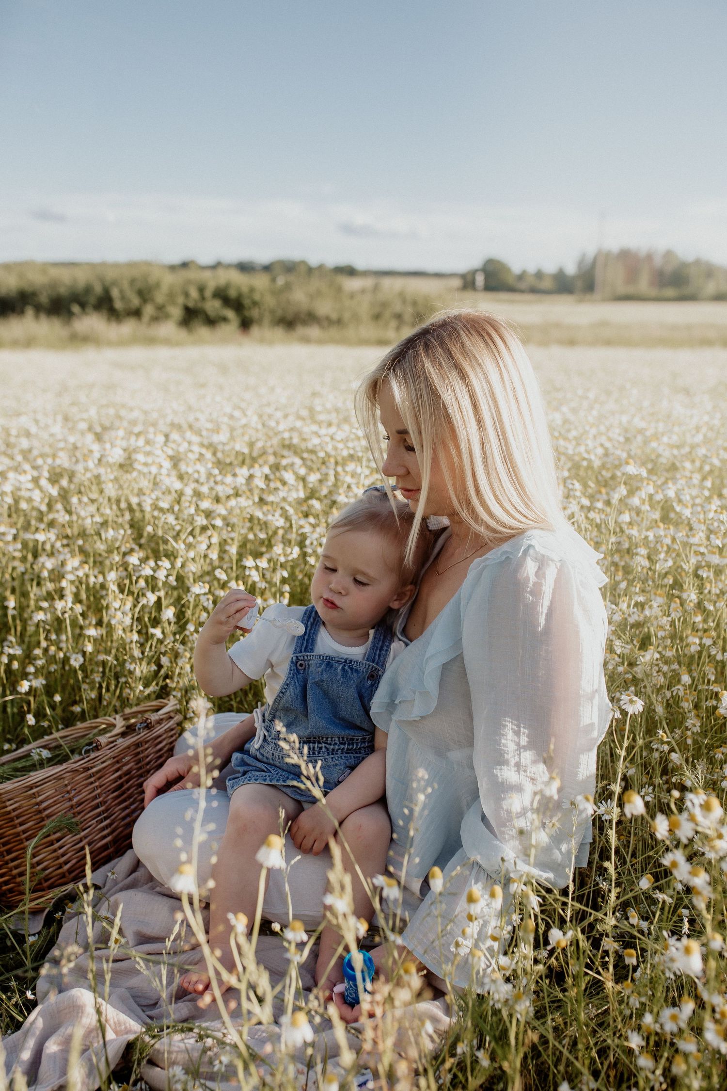 Natural family portrait of parents and children blowing bubbles together during an outdoor photography session in Latvia