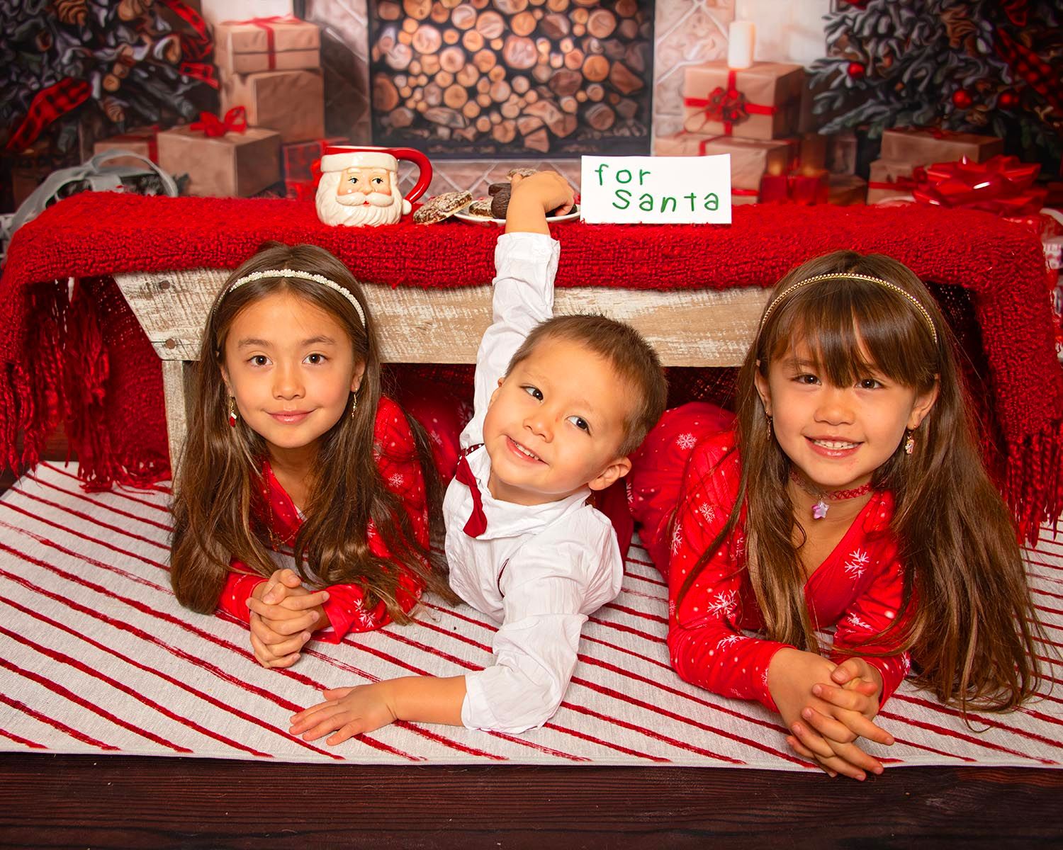 three young kids, with the boy stealing the cookie