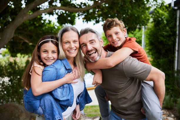 A happy group embraces and smiles together outdoors during a casual photo session in a park setting.