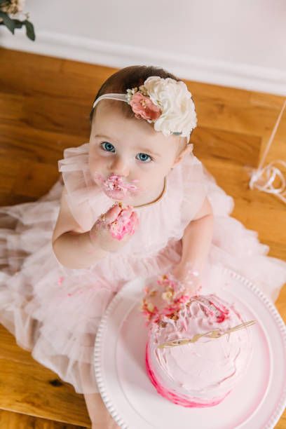 A pink frosted smash cake sits ready for a special celebration on a wooden table.
