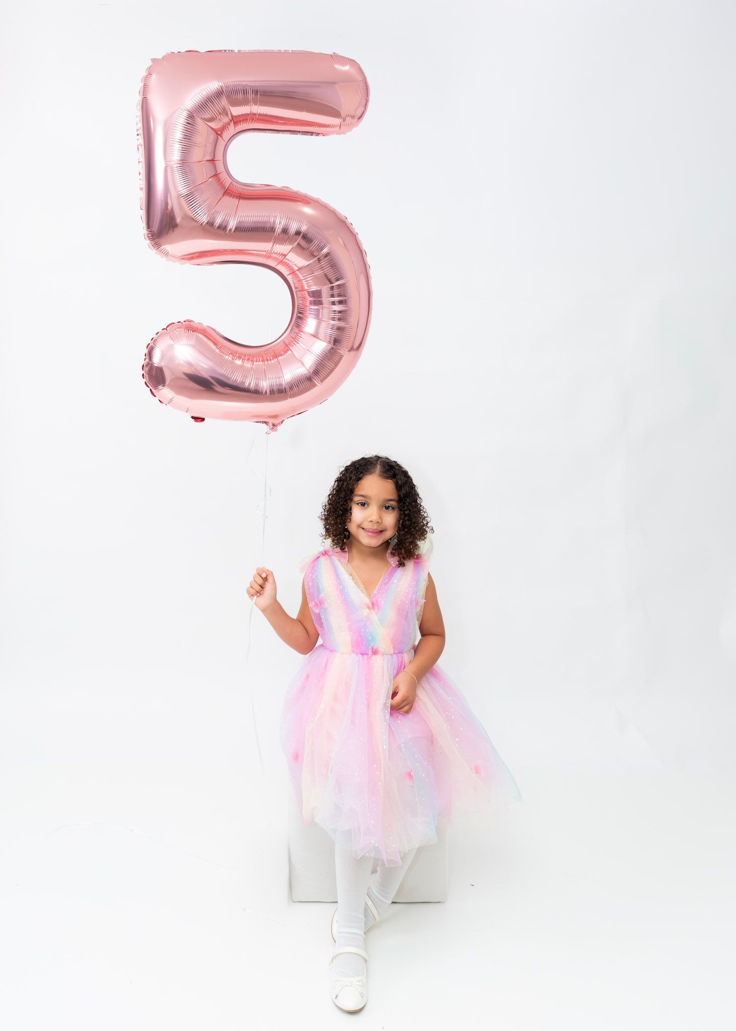 Pink number 5 balloon with festive party dress against white background.