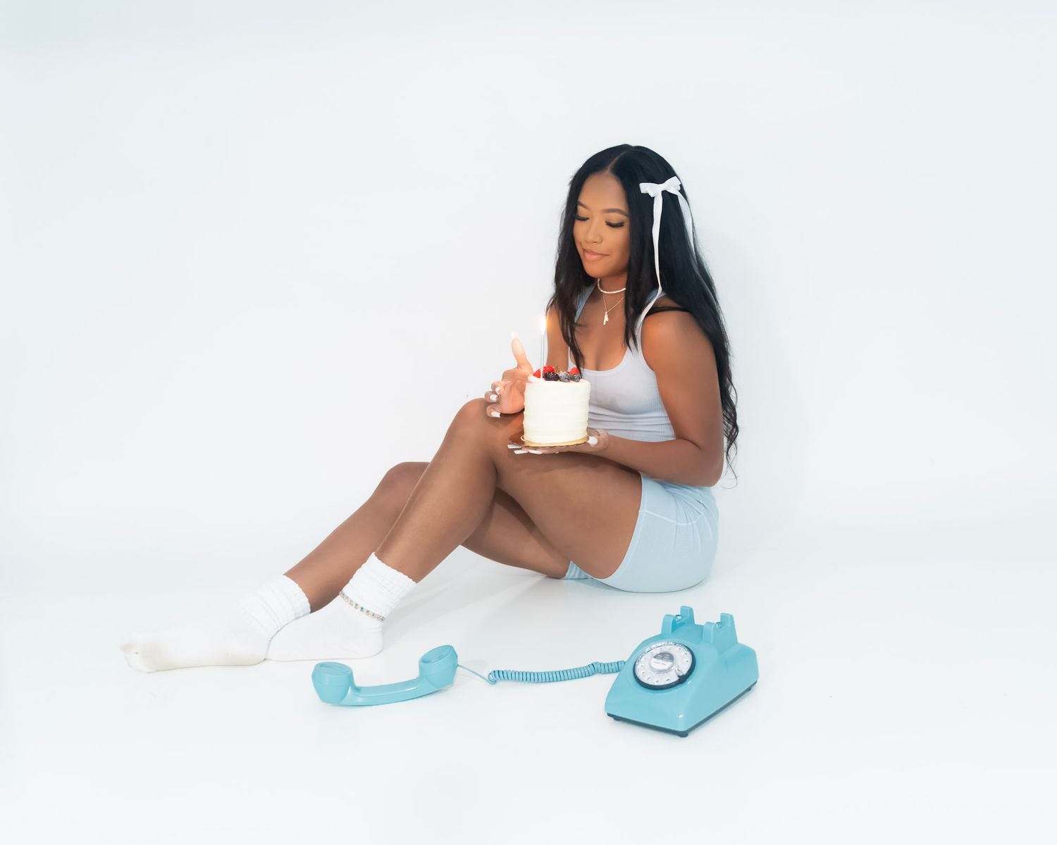 Minimalist white studio photoshoot with soft lighting and blue bow accents.