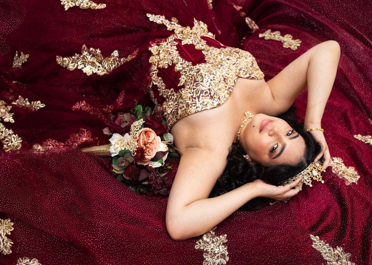 Dramatic boudoir photography on deep burgundy velvet with dried floral elements.