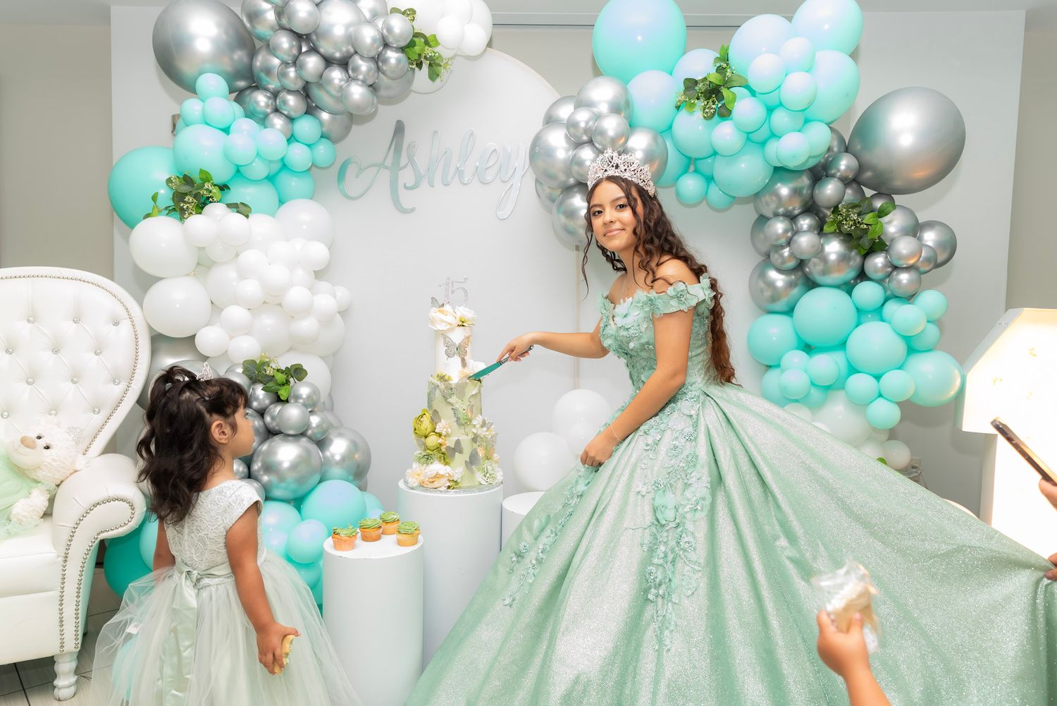 A mint green ballgown sparkles under elegant balloon decorations at a special celebration.