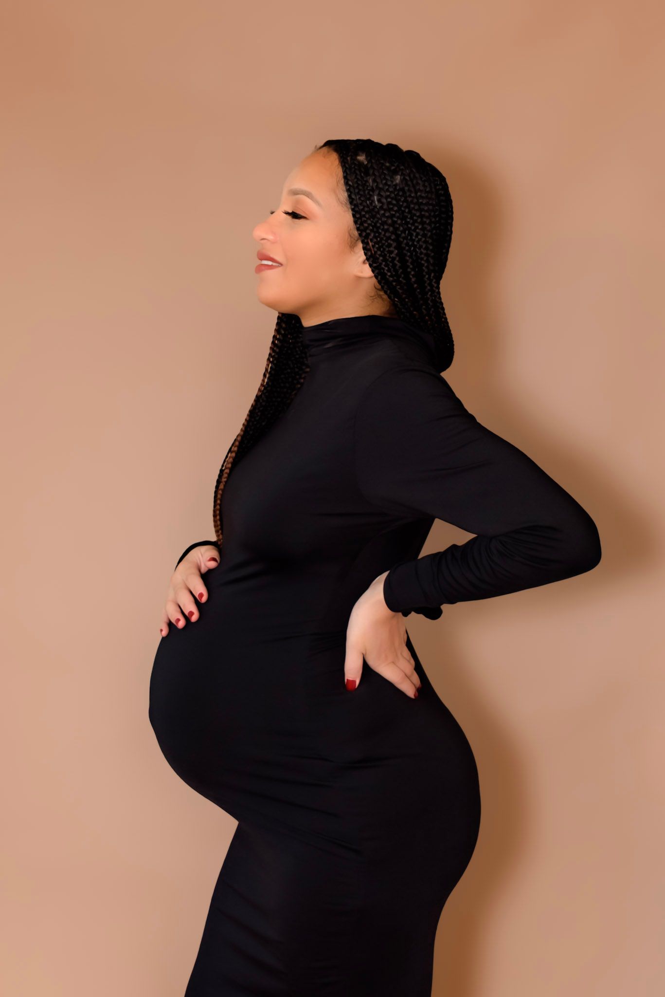 A series of maternity photos showing a woman in black against a beige background posing to highlight her pregnancy.