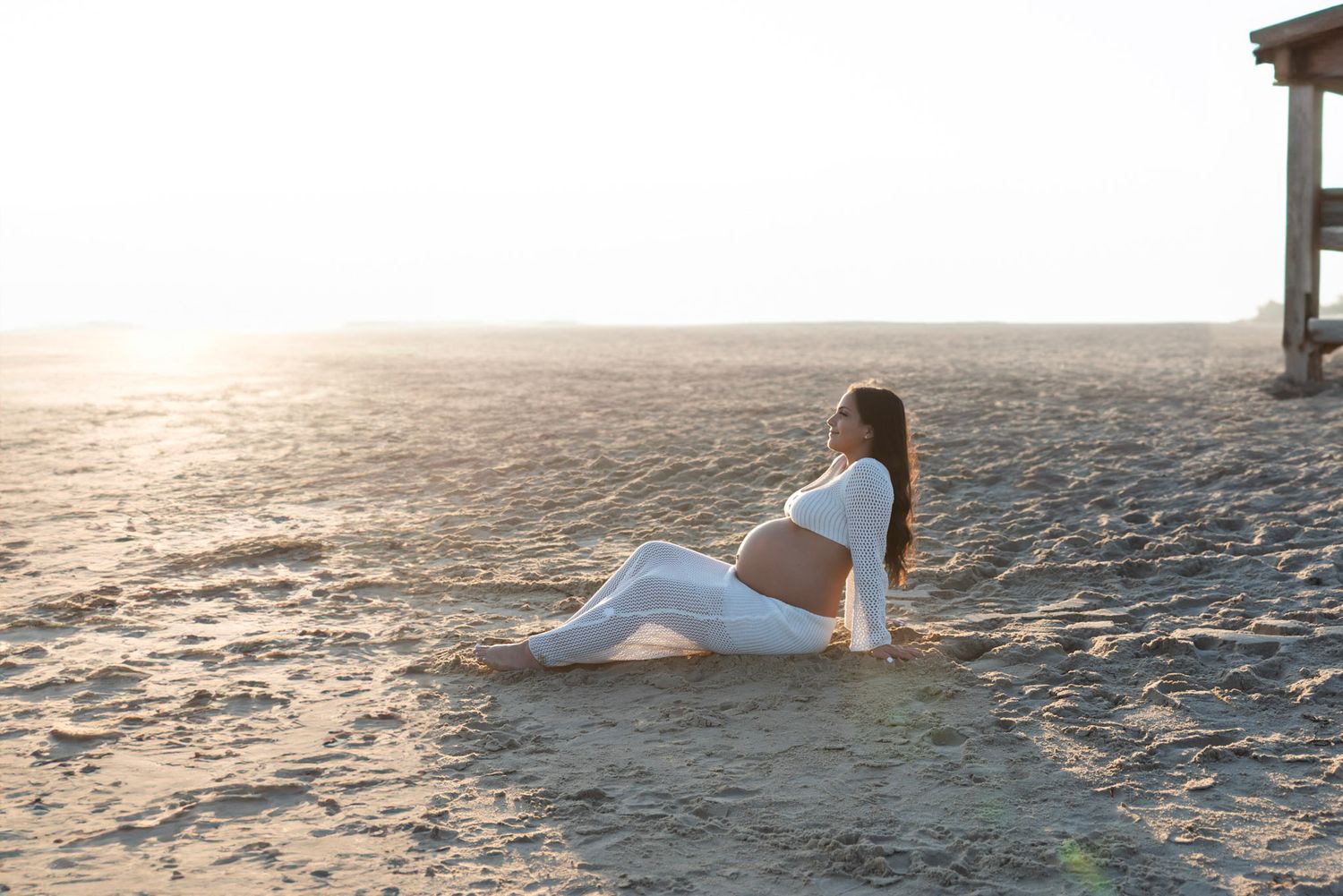 Sunset beach photoshoot with soft golden light reflecting on sand and water.