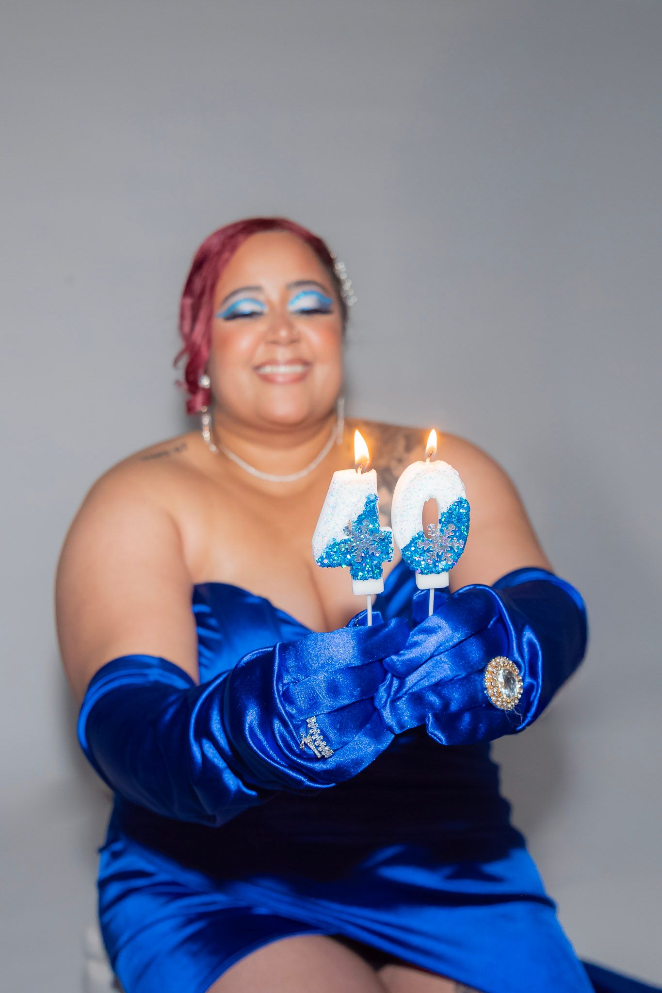 Birthday Photoshoot featuring A birthday celebration with a royal blue dress and lit candles against a gray backdrop.