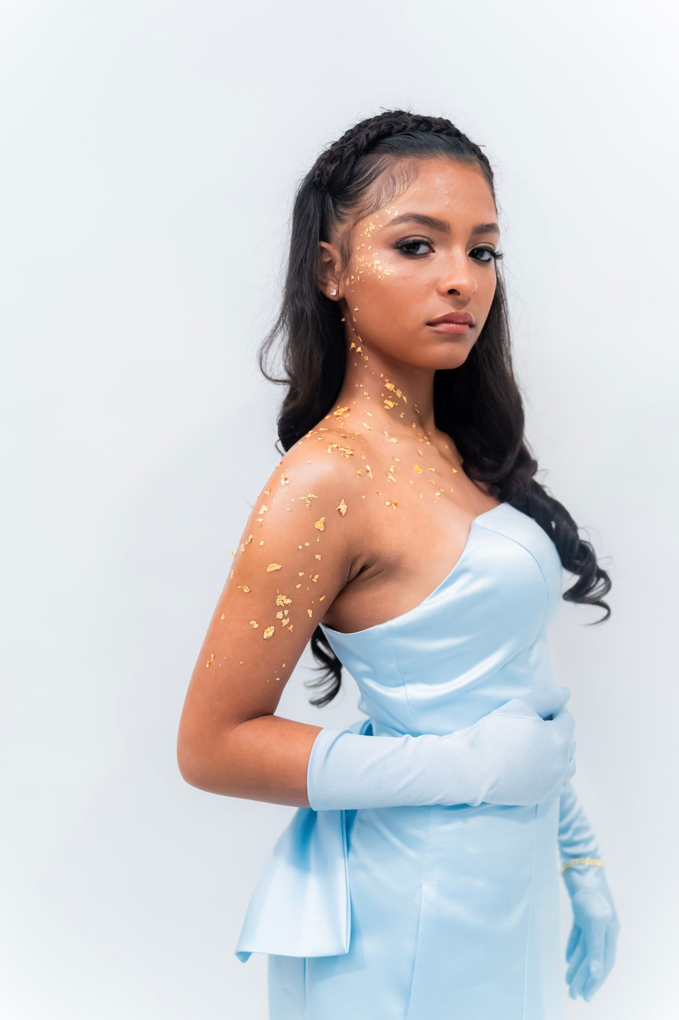 Elegant light blue dress with gold sparkle details against white background.