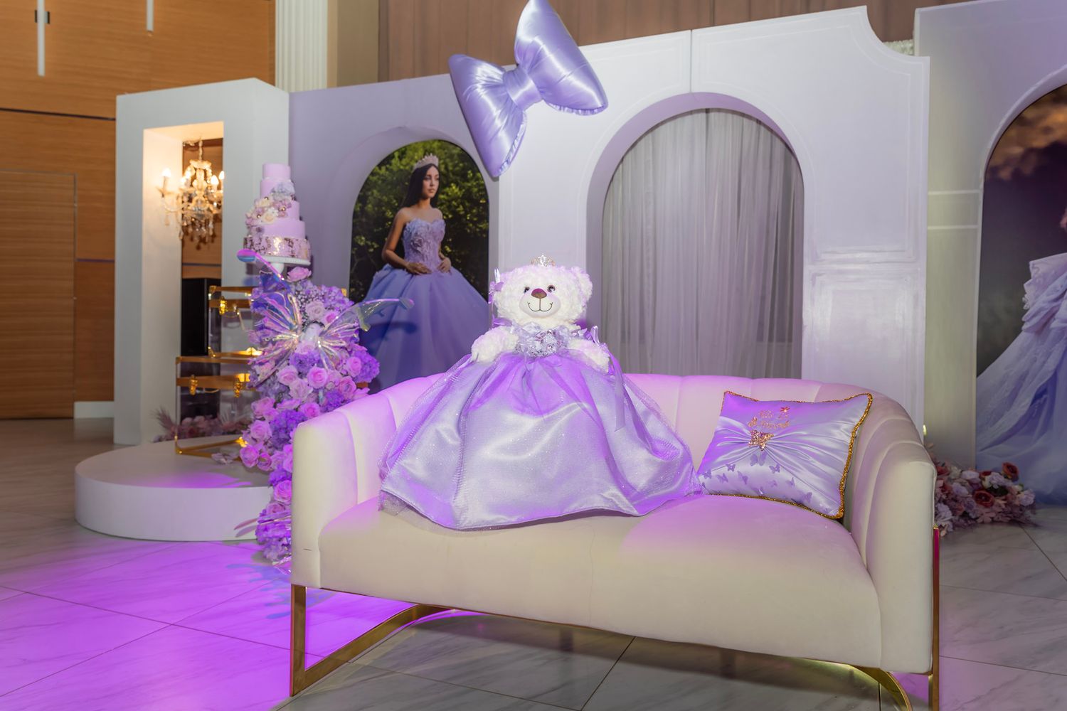 Purple and white decorative display with elegant couch and glowing lighting in an event space.