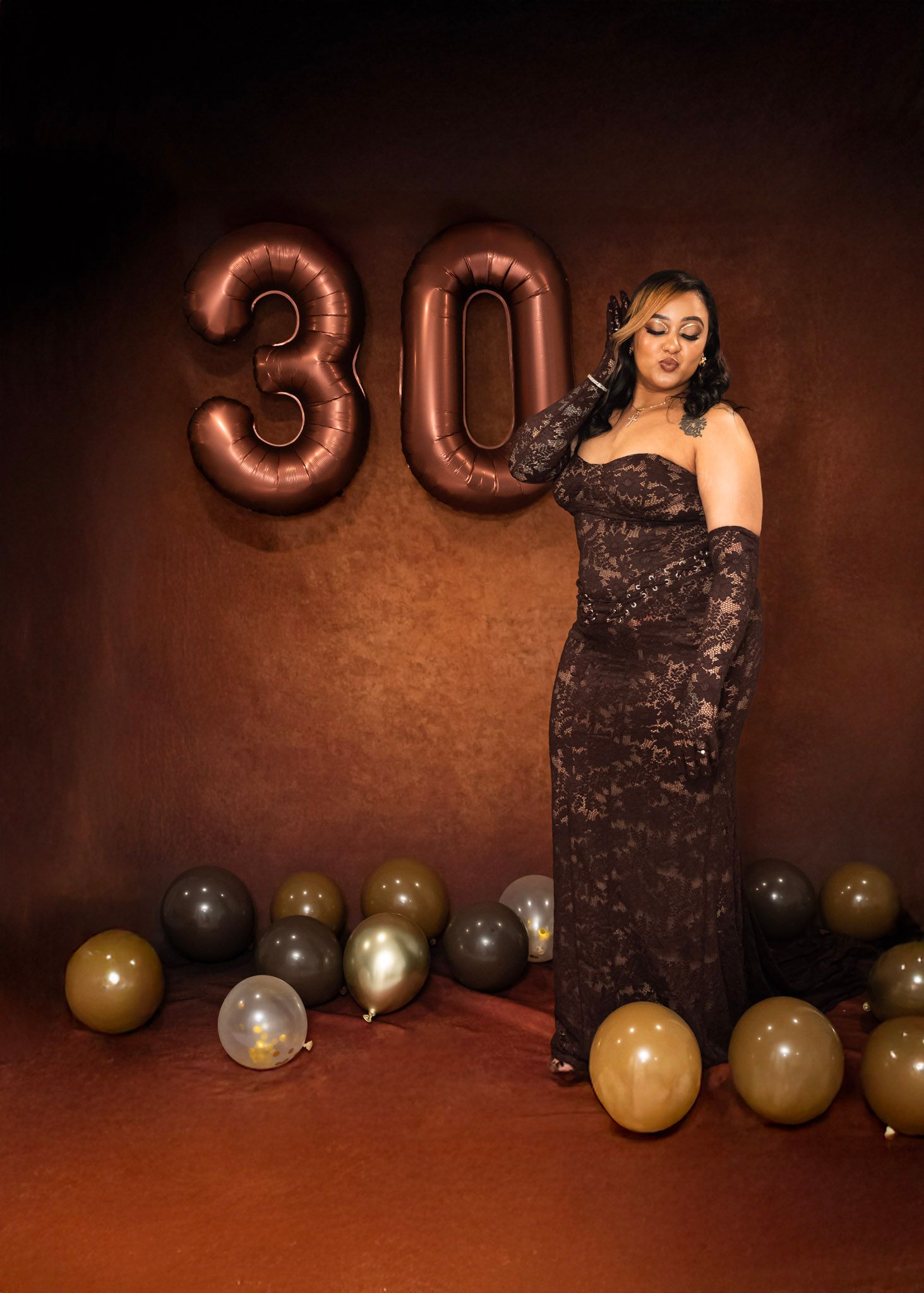 Birthday Photoshoot featuring Birthday celebration setup with metallic balloons and dark lace dress against brown backdrop.