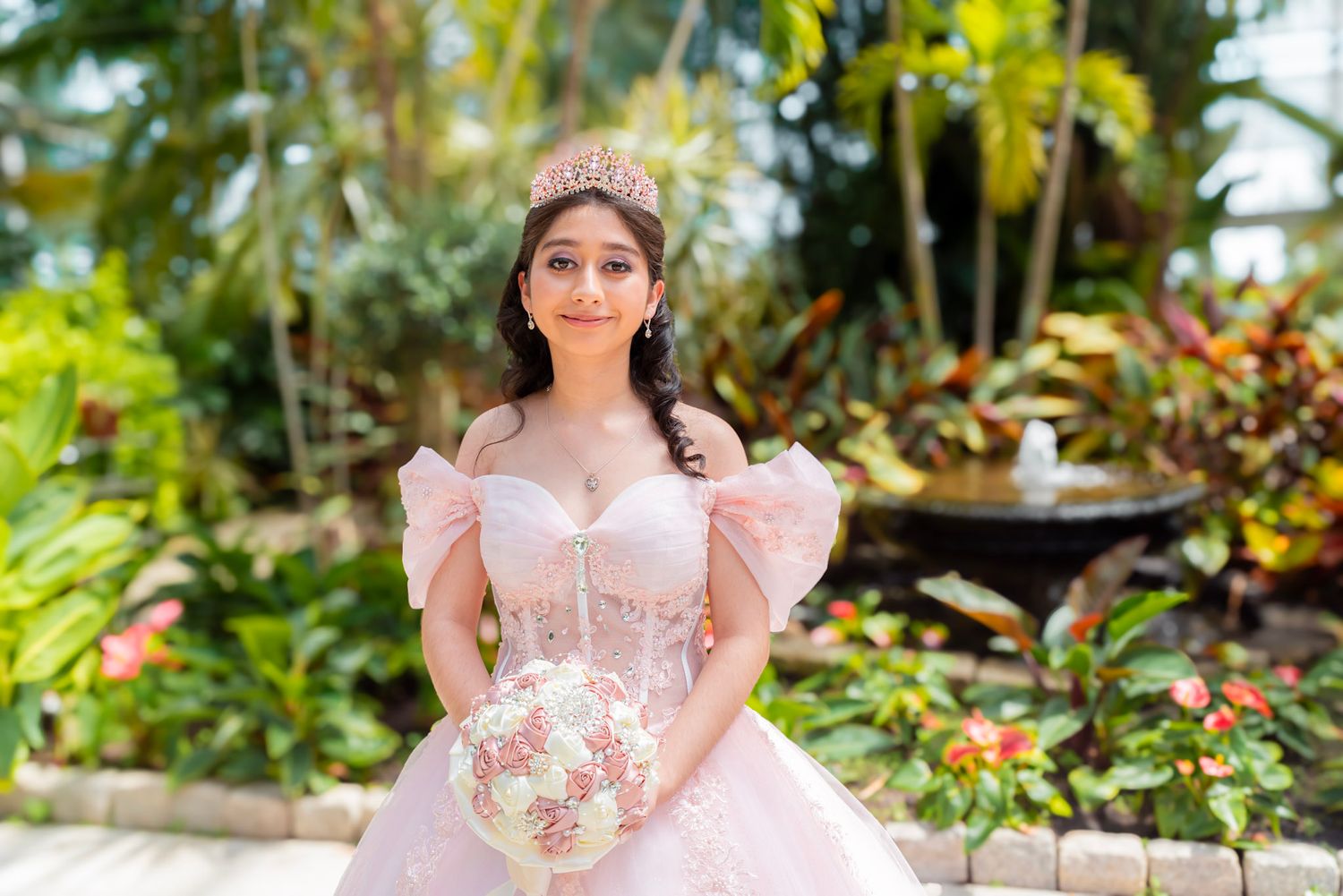 Pink princess gown with floral details in a lush tropical garden setting.