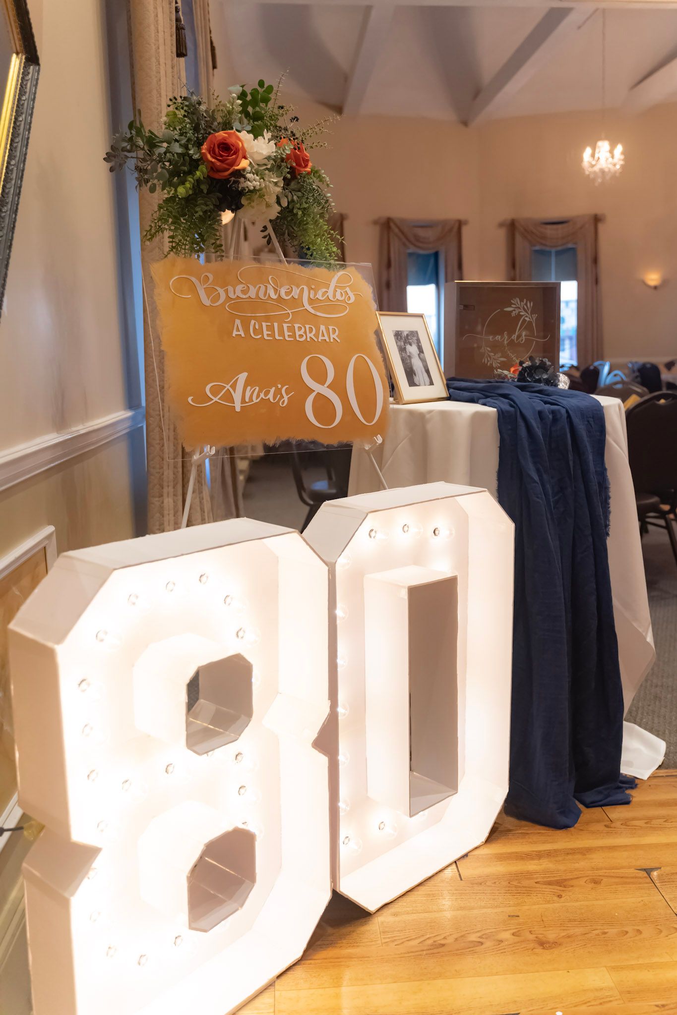 Large white decorative letters spelling out a word arranged on a wooden floor at an event venue.