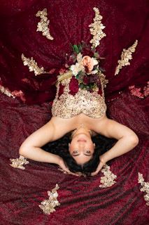 Artistic poses on burgundy velvet with gold accents creating dramatic contrast.
