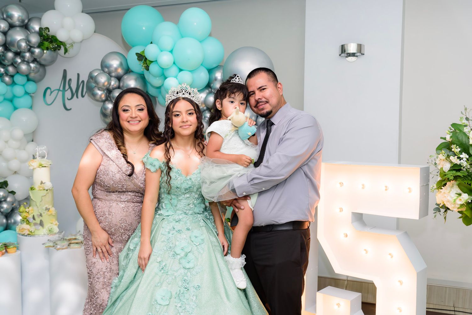 Family gathering with mint green decor and balloons at an elegant indoor party venue.