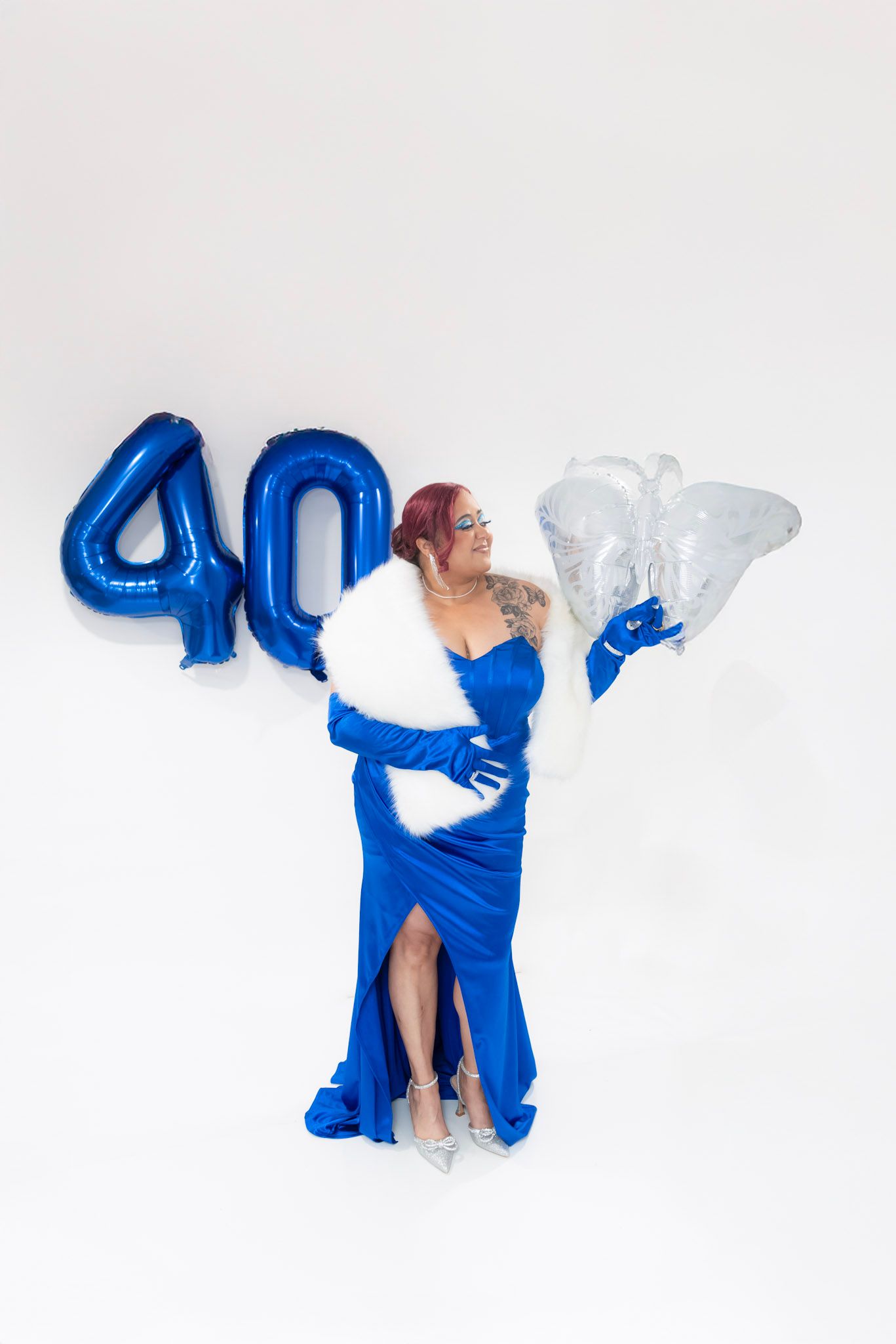 A celebratory scene with blue number 40 balloons and a flowing royal blue dress against a white background.