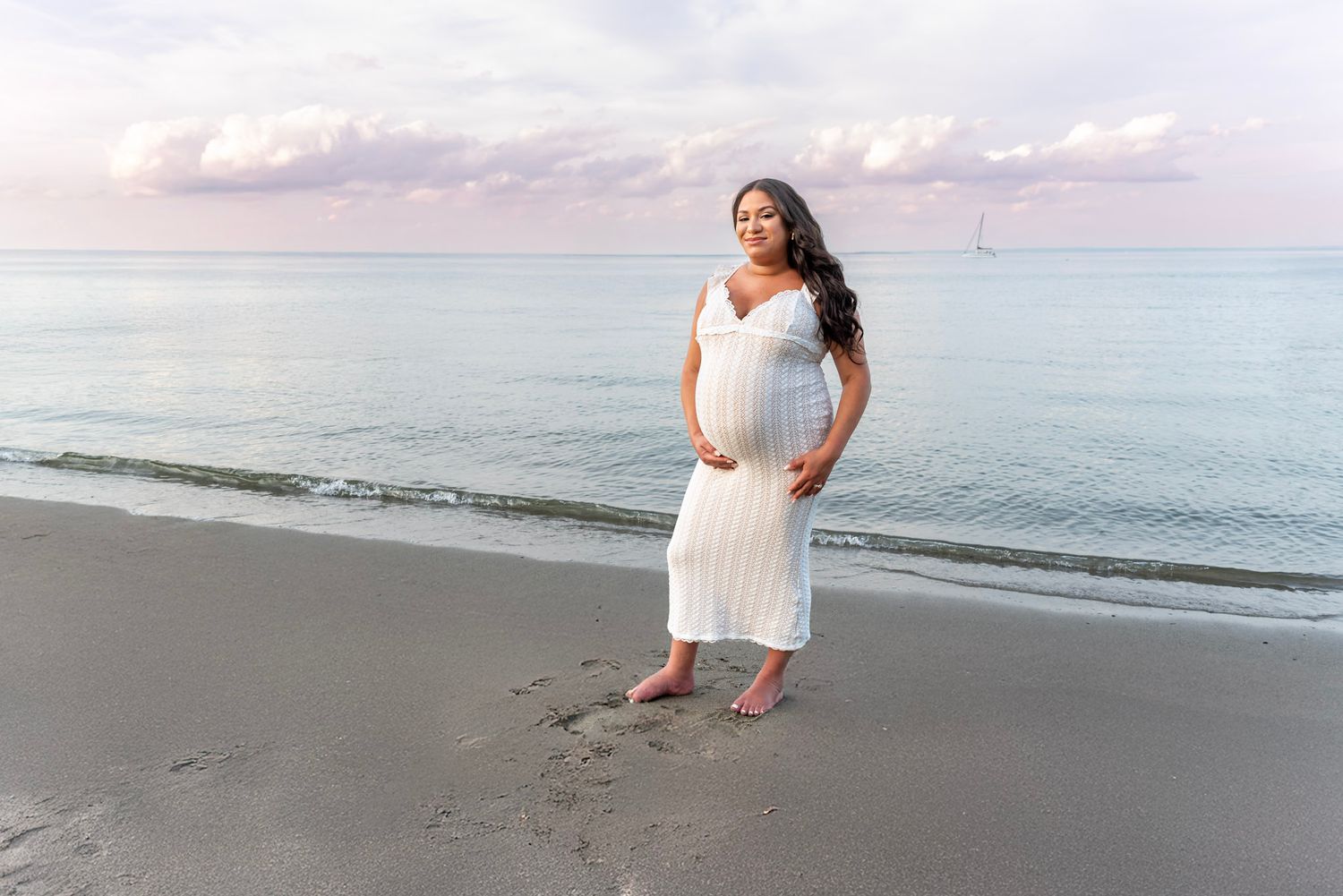 Serene beach photoshoot at sunset with soft pastel colors in the sky.