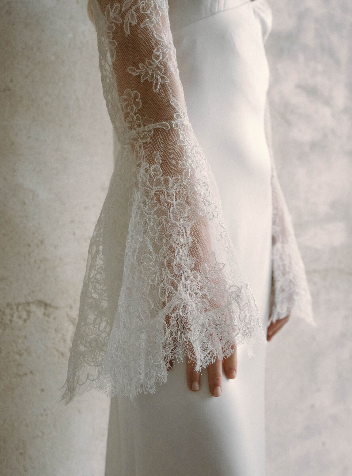 Detail shot of delicate white lace trim on wedding dress sleeve.